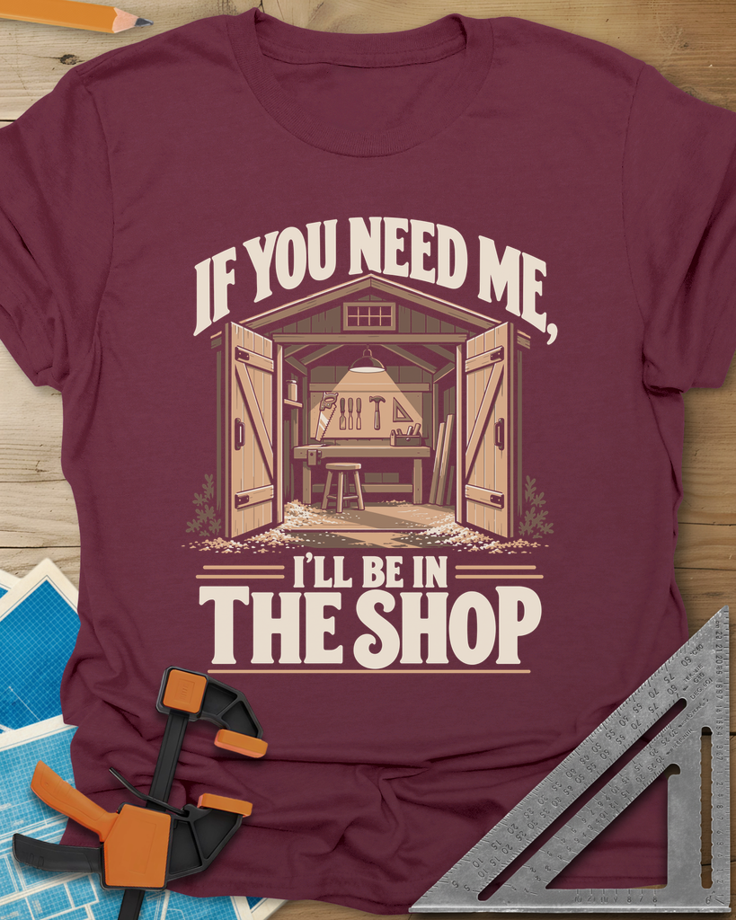 In The Shop t-shirt in Maroon, a small open workshop with a hanging lamp, bench and wall tools