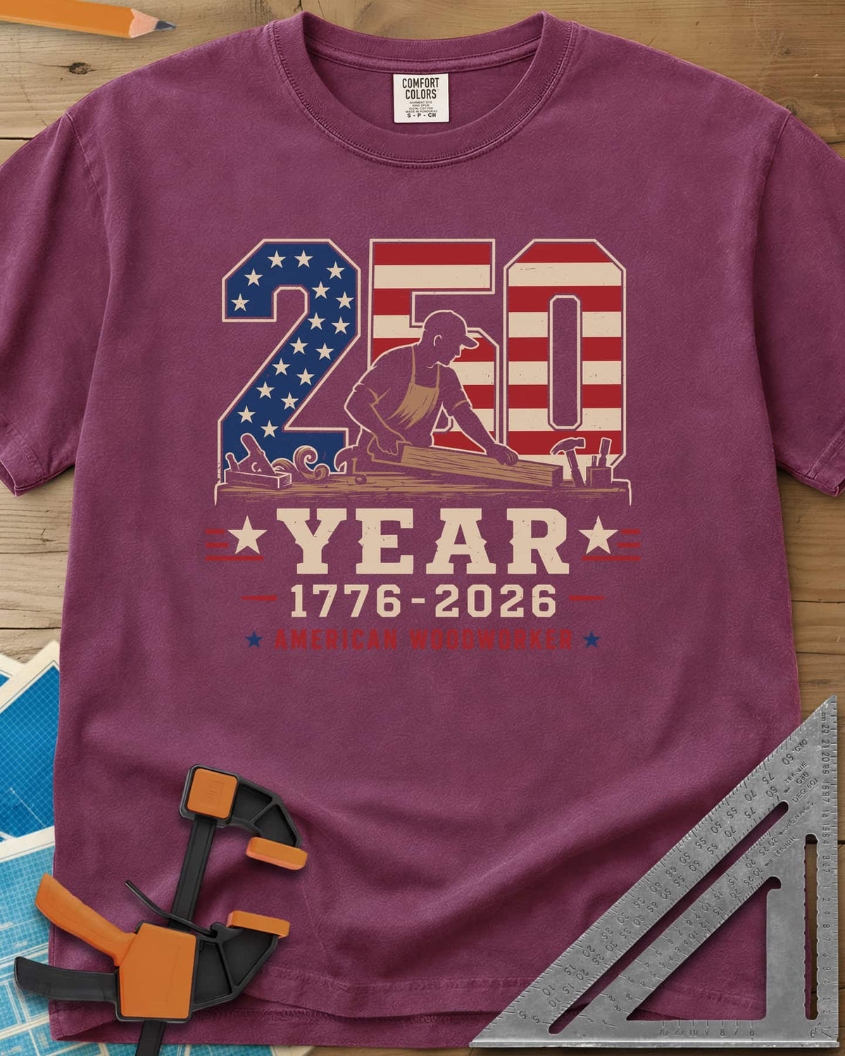 250 Year American Woodworker heavyweight tee in Berry, stars-and-stripes 250 with a woodworker planing a board