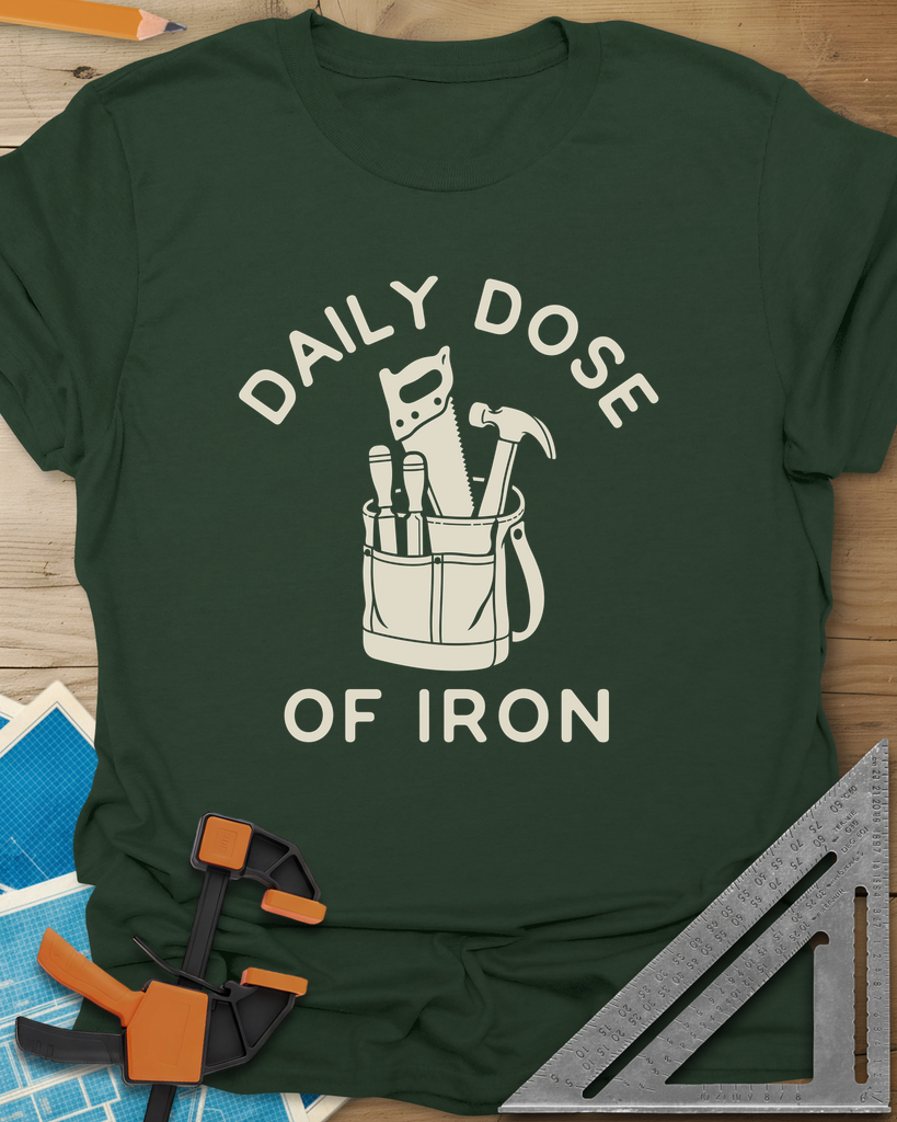 Daily Dose t-shirt in Forest Green, a canvas tool bag holding a handsaw, hammer and two chisels