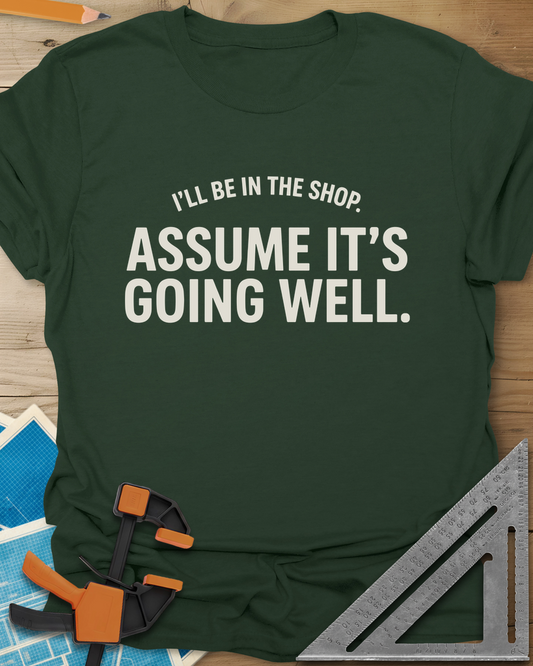 Assume It's Going Well t-shirt in Forest Green, bold two-line lettering with a small arched line above