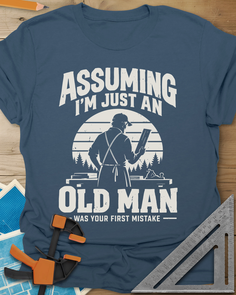 Old Man Mistake t-shirt in Indigo Blue, a woodworker in an apron holding a board before a striped sunset