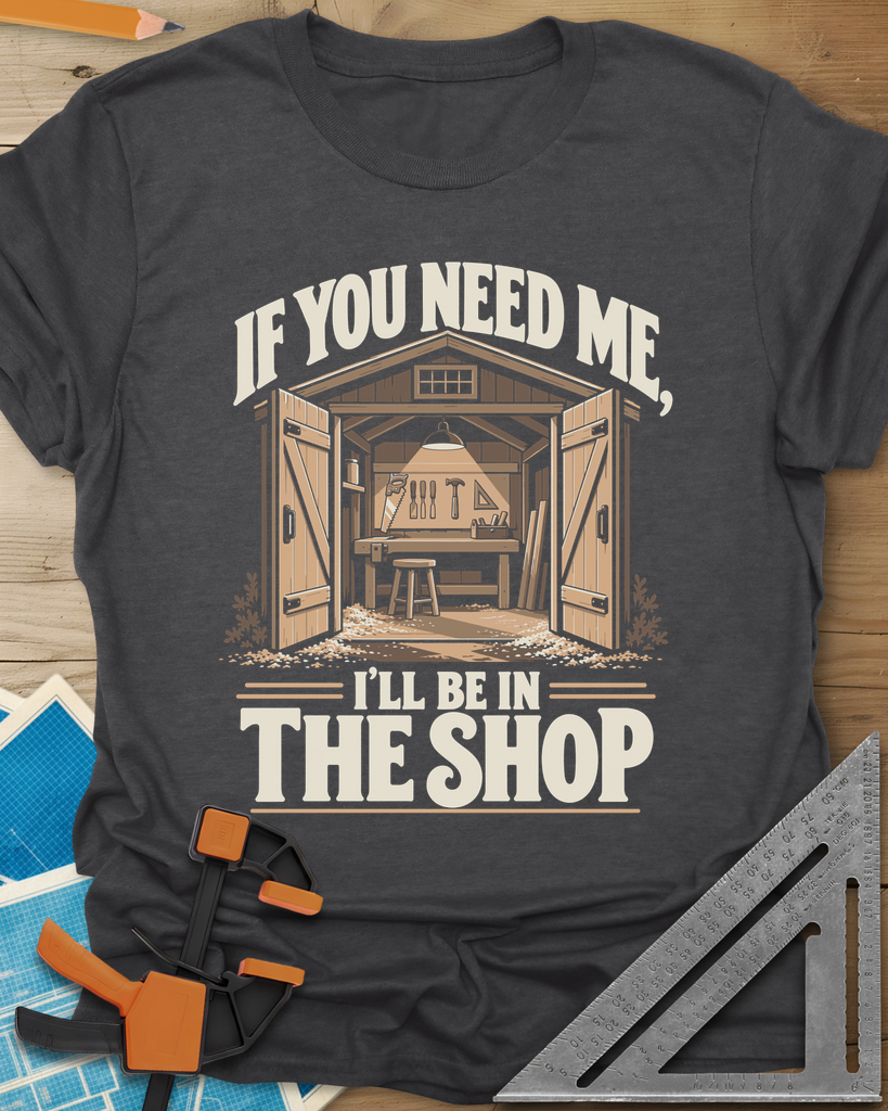 In The Shop t-shirt in Dark Heather Grey, a small open workshop with a hanging lamp, bench and wall tools