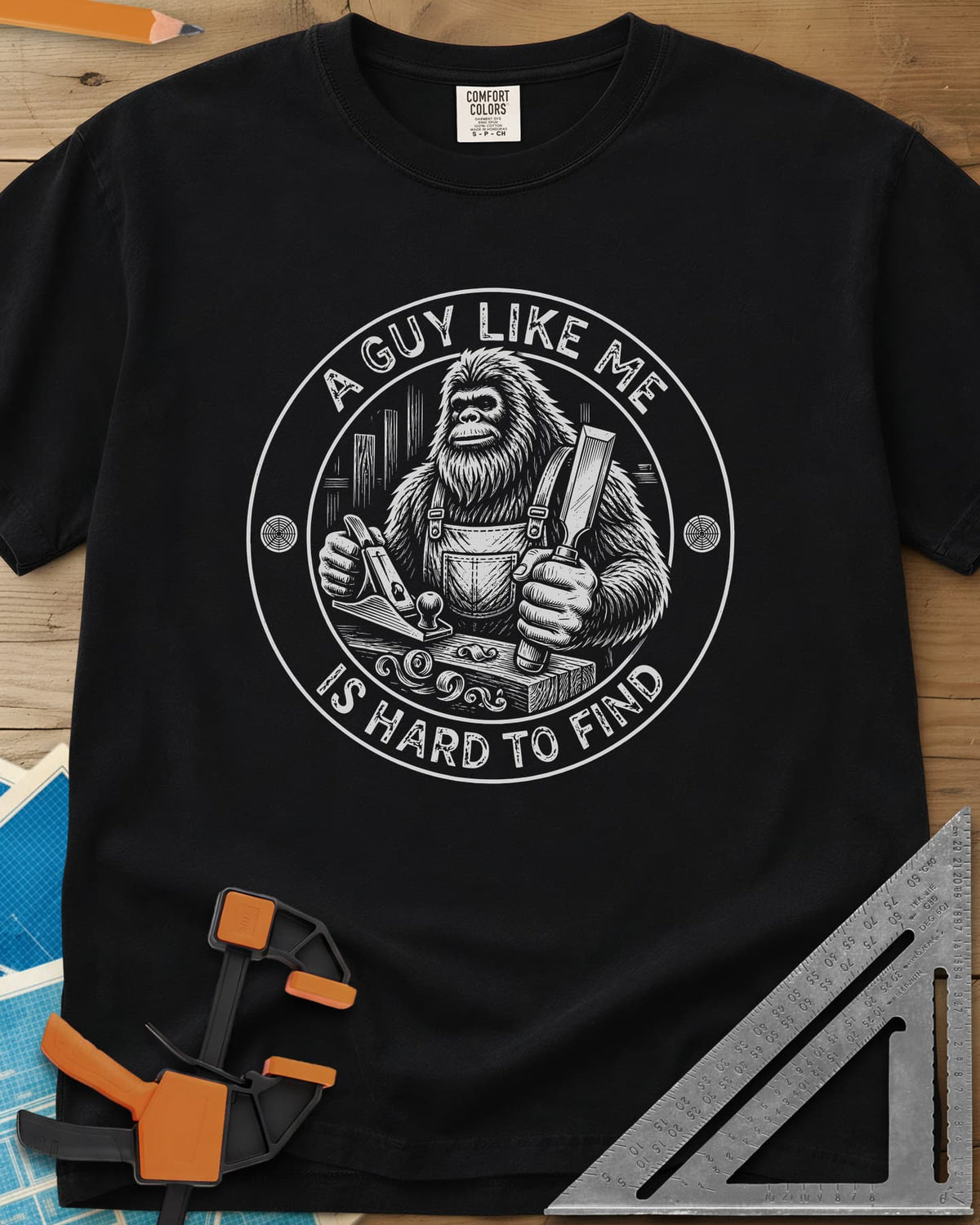 A Guy Like Me Is Hard To Find Woodworking heavyweight tee in Black, Bigfoot in overalls with a hand plane and chisel inside