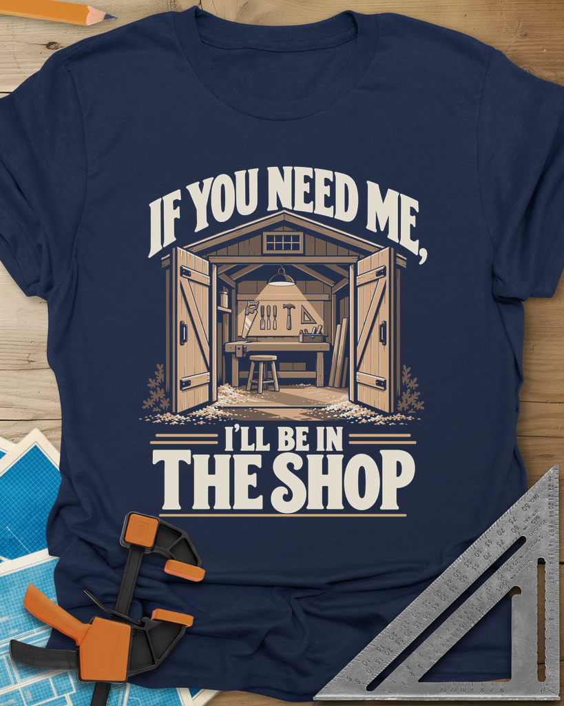 In The Shop t-shirt in Navy, a small open workshop with a hanging lamp, bench and wall tools