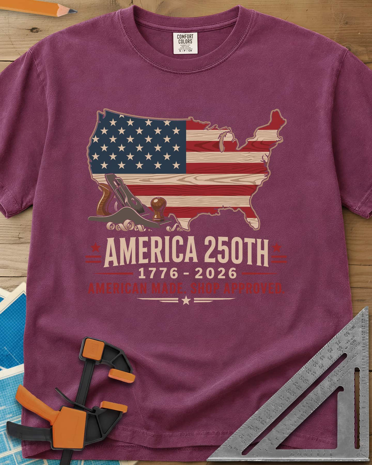 America 250th Shop Approved heavyweight tee in Berry, a US map filled with a wood-plank flag, a hand plane and curls
