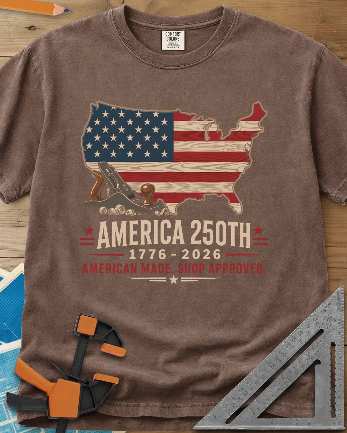 America 250th Shop Approved heavyweight tee in Espresso, a US map filled with a wood-plank flag, a hand plane and curls