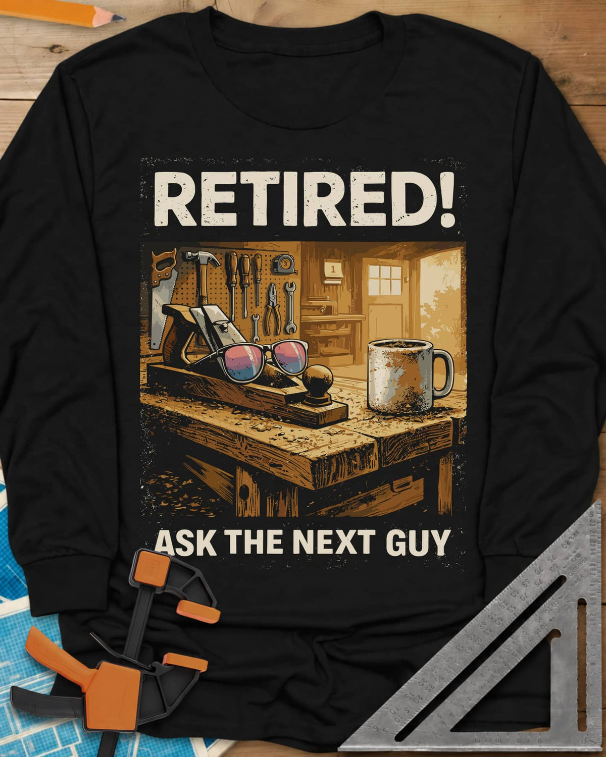 Ask The Next Guy long sleeve shirt in Black, a sunlit workbench with a hand plane, sunglasses and a coffee mug
