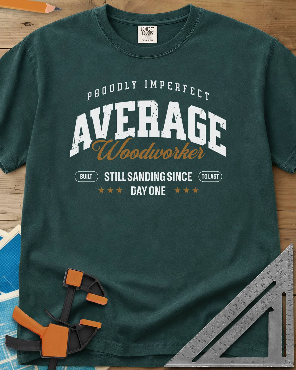 Average Woodworker heavyweight tee in Blue Spruce, varsity AVERAGE over gold script Woodworker, with badges and stars