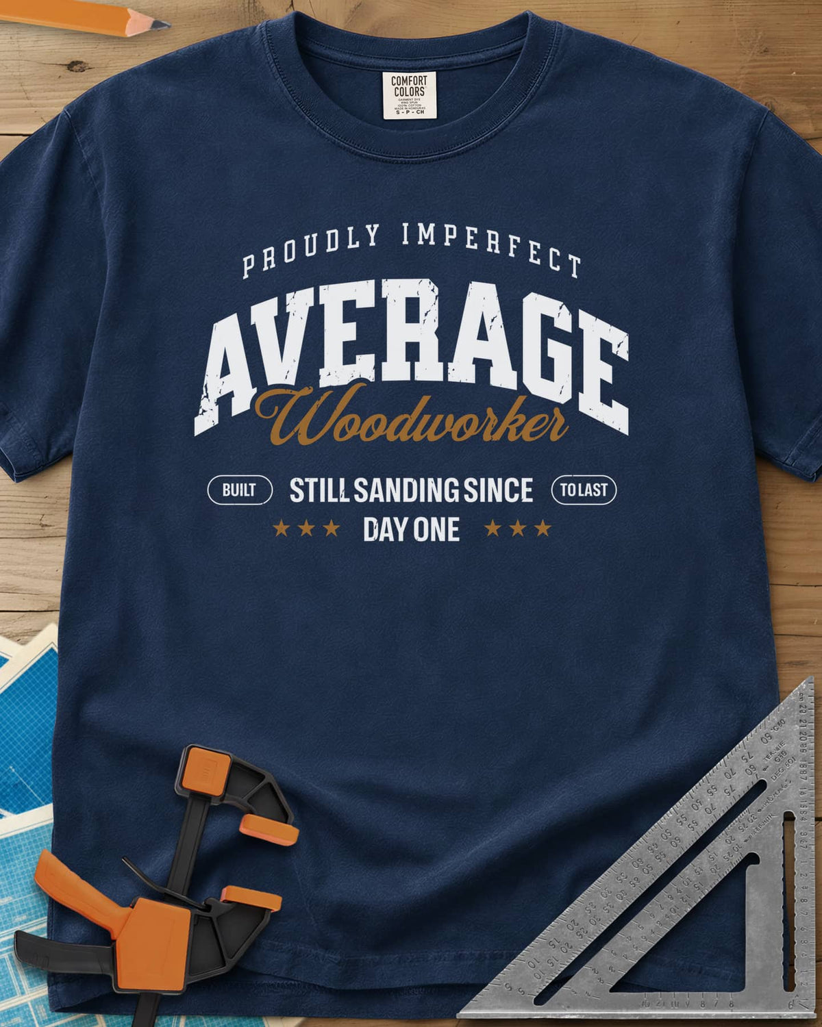 Average Woodworker heavyweight tee in Navy, varsity AVERAGE over gold script Woodworker, with badges and stars