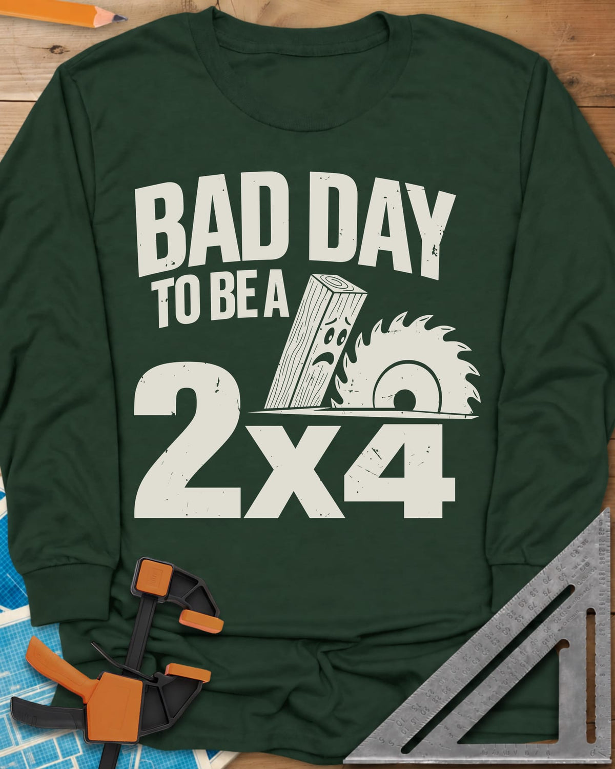 Bad Day 2x4 long sleeve shirt in Forest Green, a 2x4 board with a worried face beside a circular saw blade