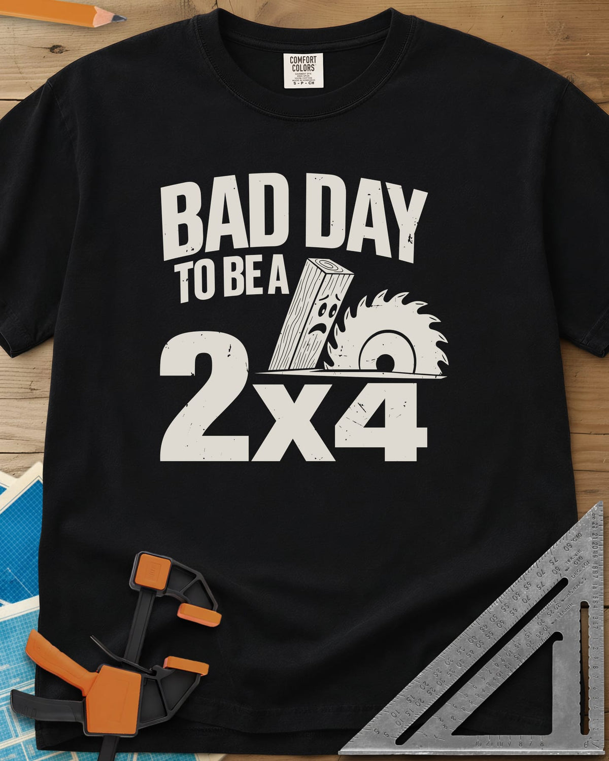 Bad Day 2x4 heavyweight tee in Black, a 2x4 board with a worried face beside a circular saw blade