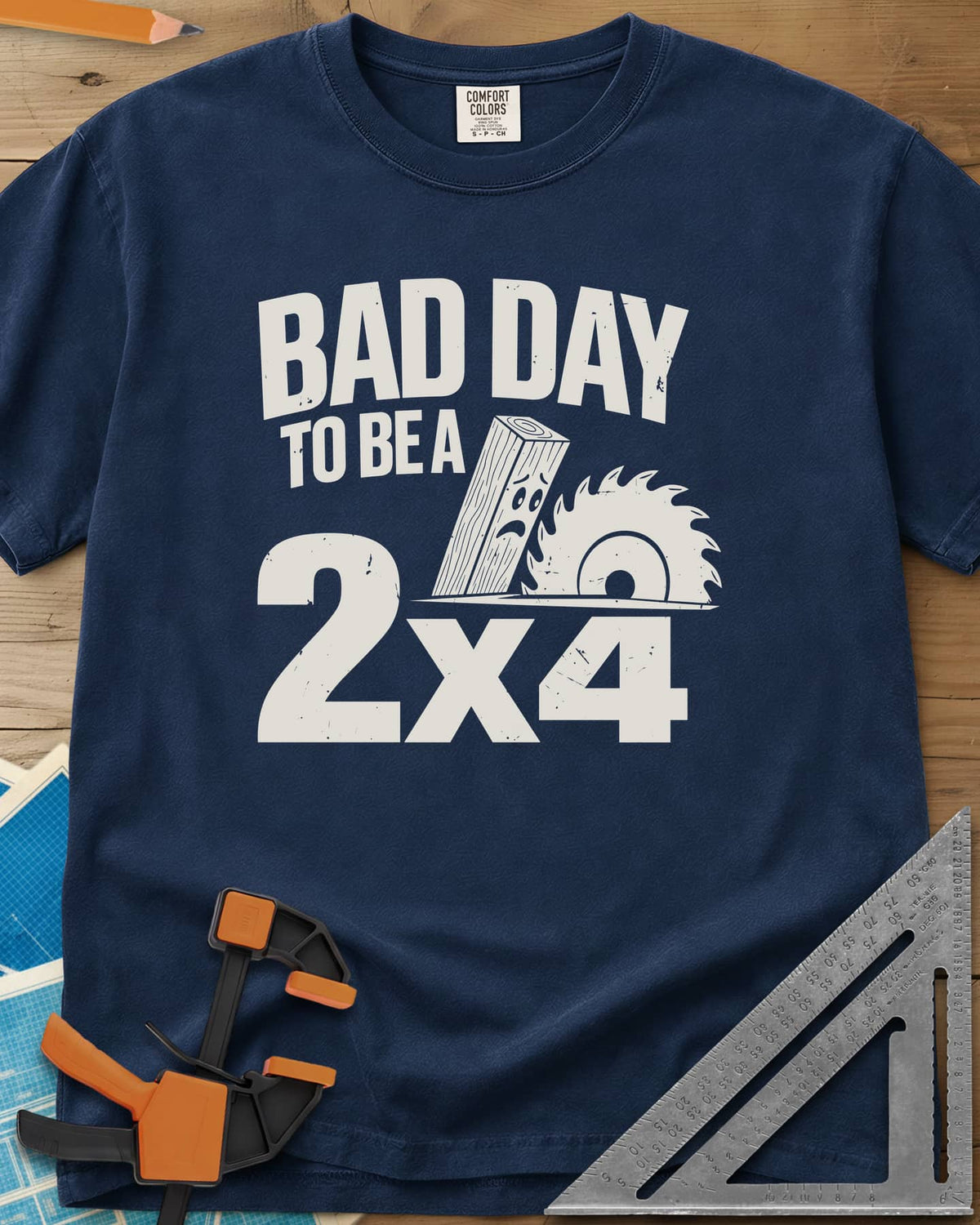 Bad Day 2x4 heavyweight tee in Navy, a 2x4 board with a worried face beside a circular saw blade