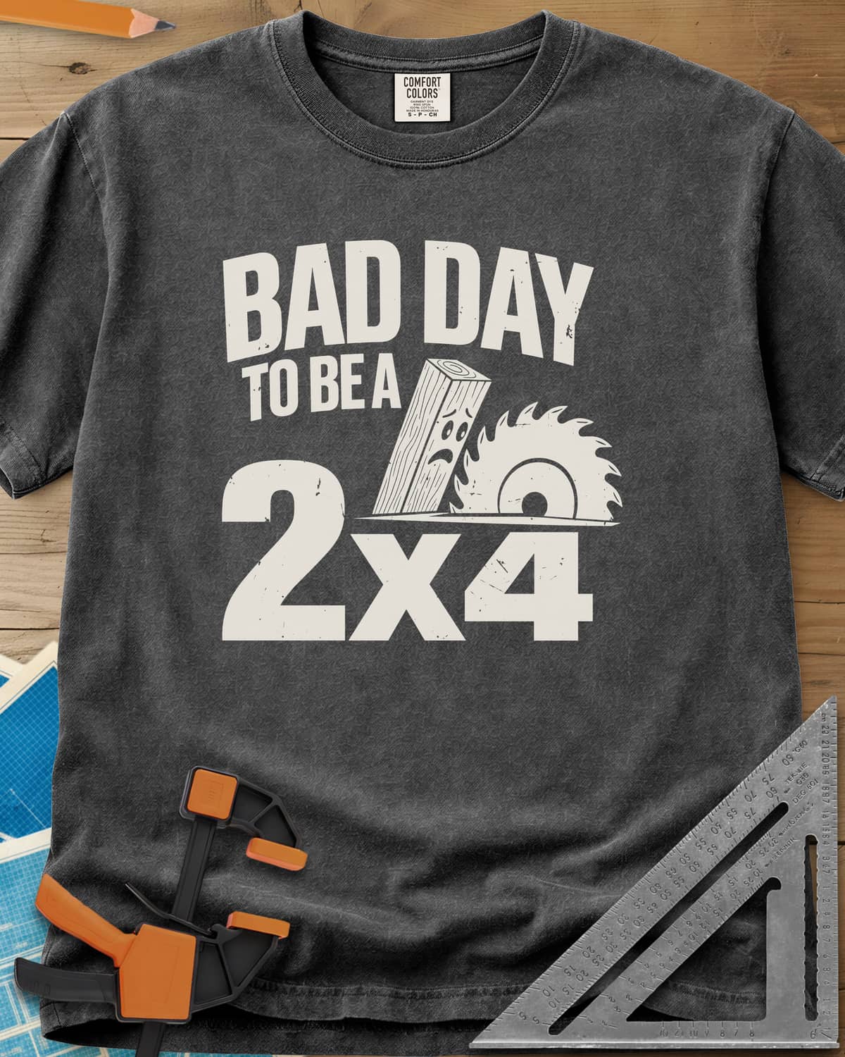 Bad Day 2x4 heavyweight tee in Pepper, a 2x4 board with a worried face beside a circular saw blade