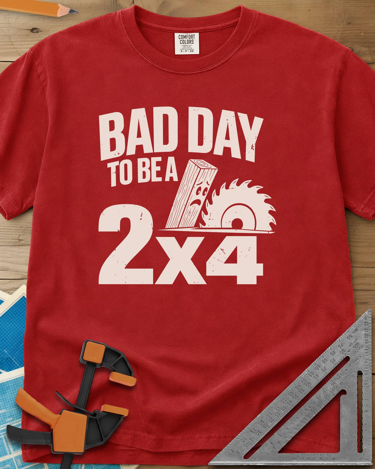 Bad Day 2x4 heavyweight tee in Red, a 2x4 board with a worried face beside a circular saw blade