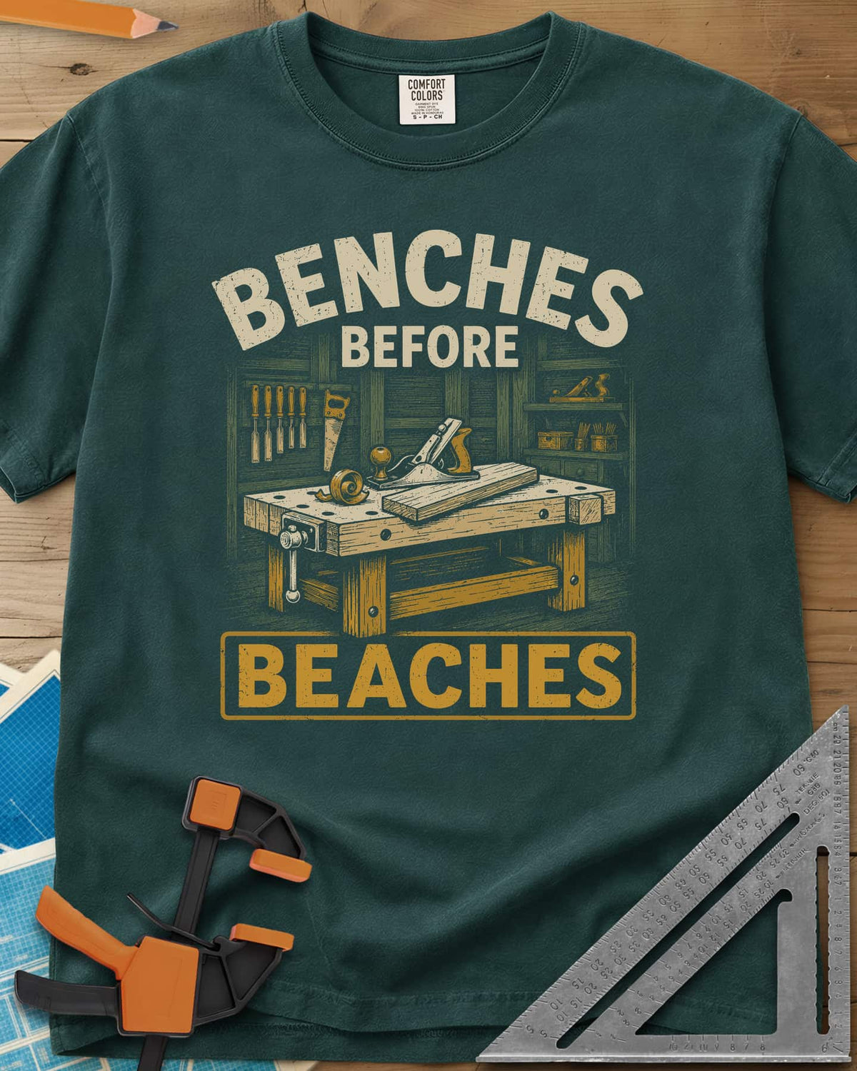 Benches Before Beaches heavyweight tee in Blue Spruce, a woodworking bench with a hand plane, chisels and a saw on the wall
