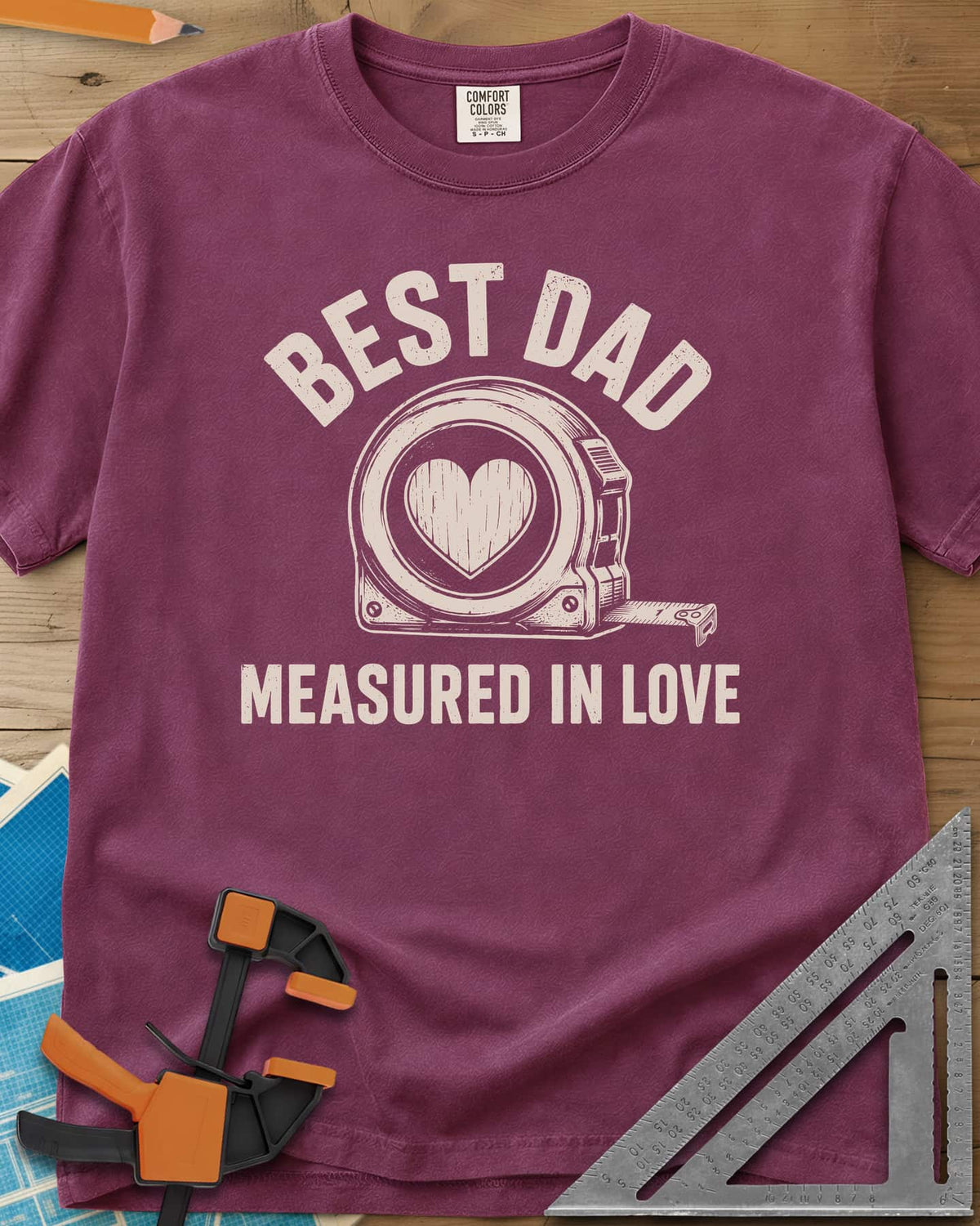 Best Dad Measured In Love heavyweight tee in Berry, a round tape measure with a wood-grain heart on its face