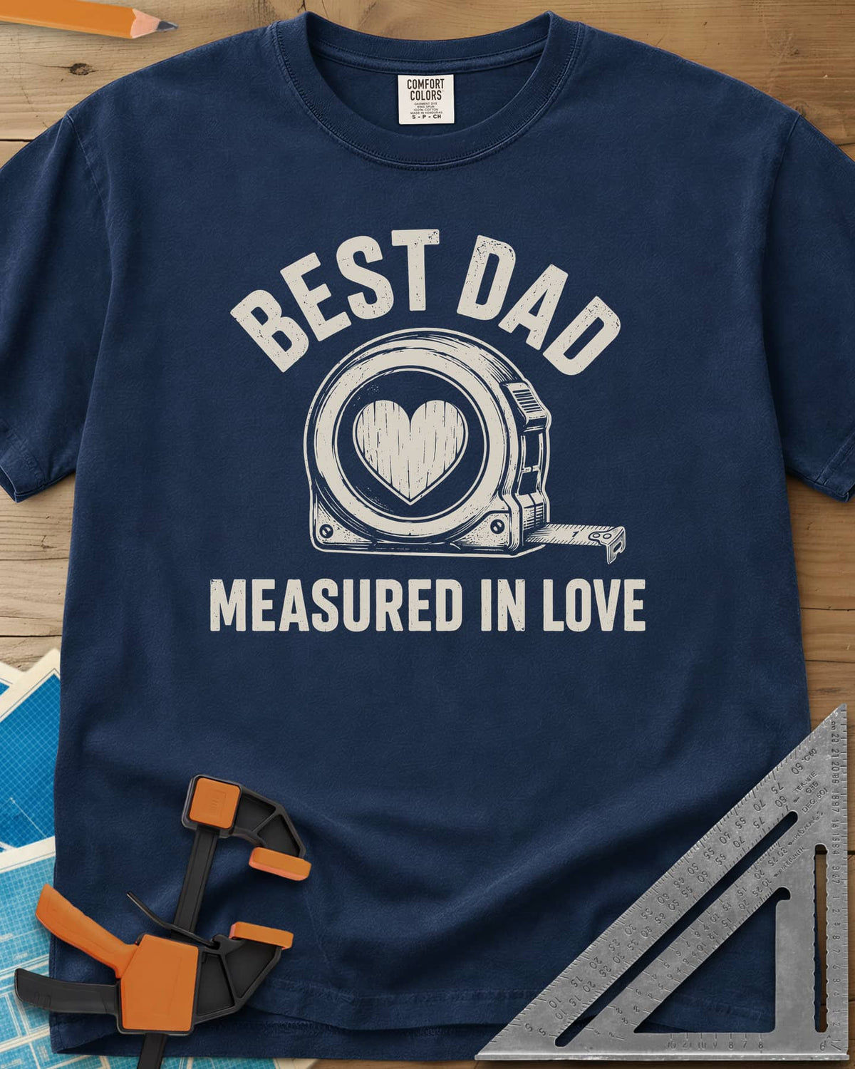 Best Dad Measured In Love heavyweight tee in Navy, a round tape measure with a wood-grain heart on its face