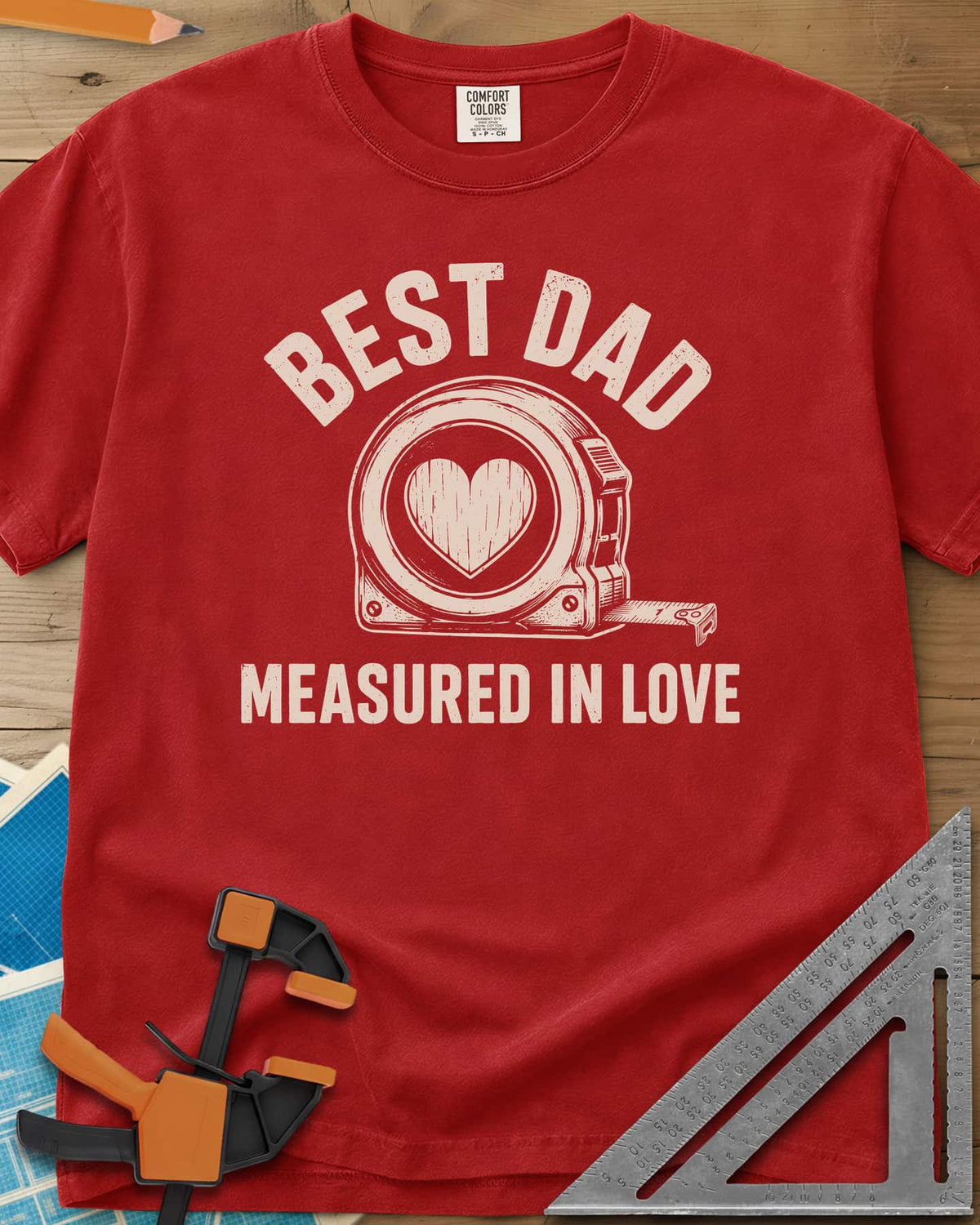 Best Dad Measured In Love heavyweight tee in Red, a round tape measure with a wood-grain heart on its face