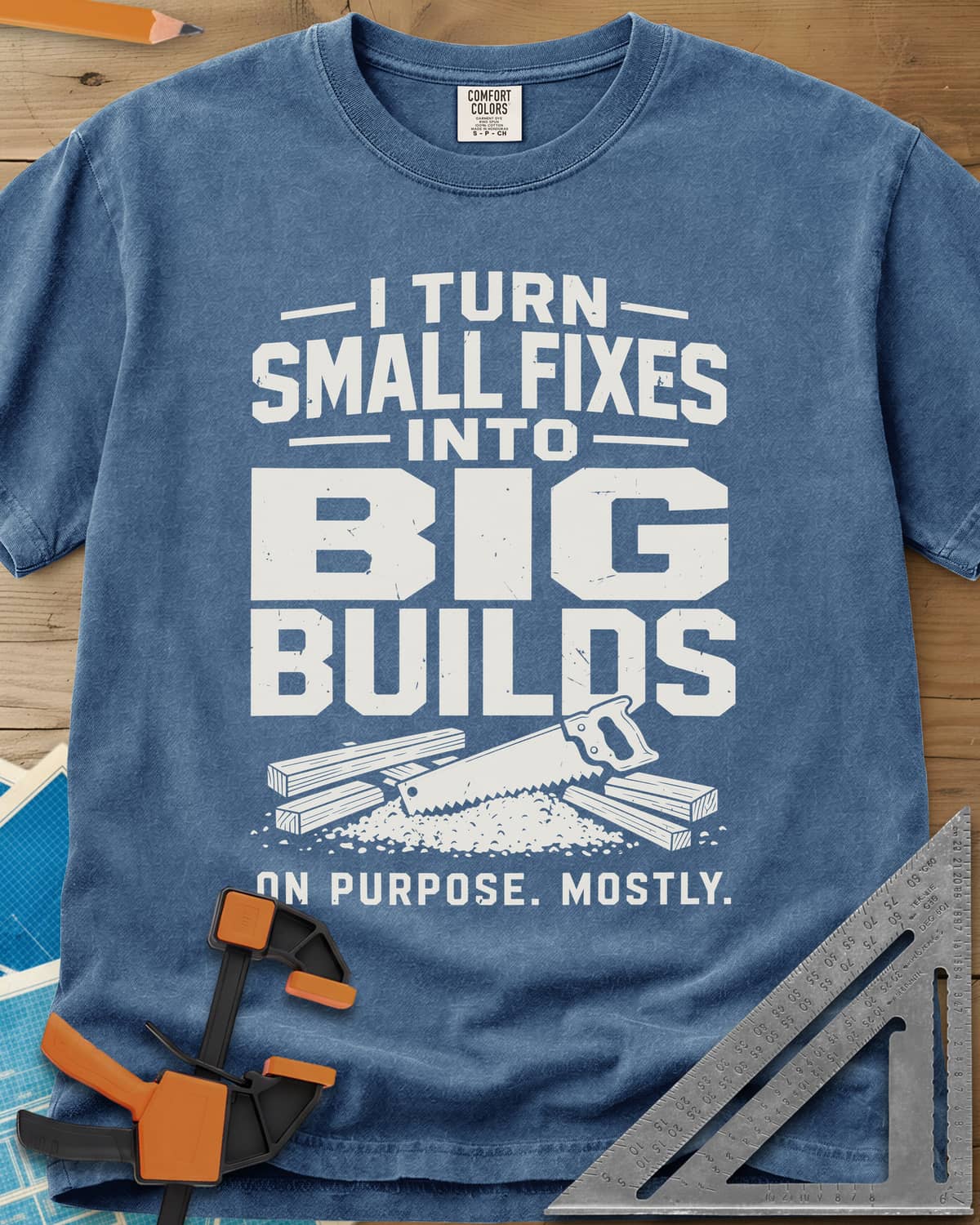 Big Builds heavyweight tee in Blue Jean, a handsaw resting on cut boards and a heap of sawdust