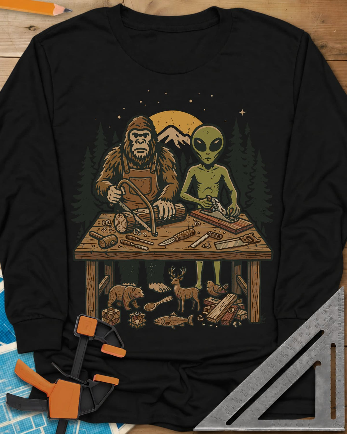 Bigfoot And Alien Woodshop long sleeve shirt in Black, Bigfoot sawing a log and an alien planing a board at one bench