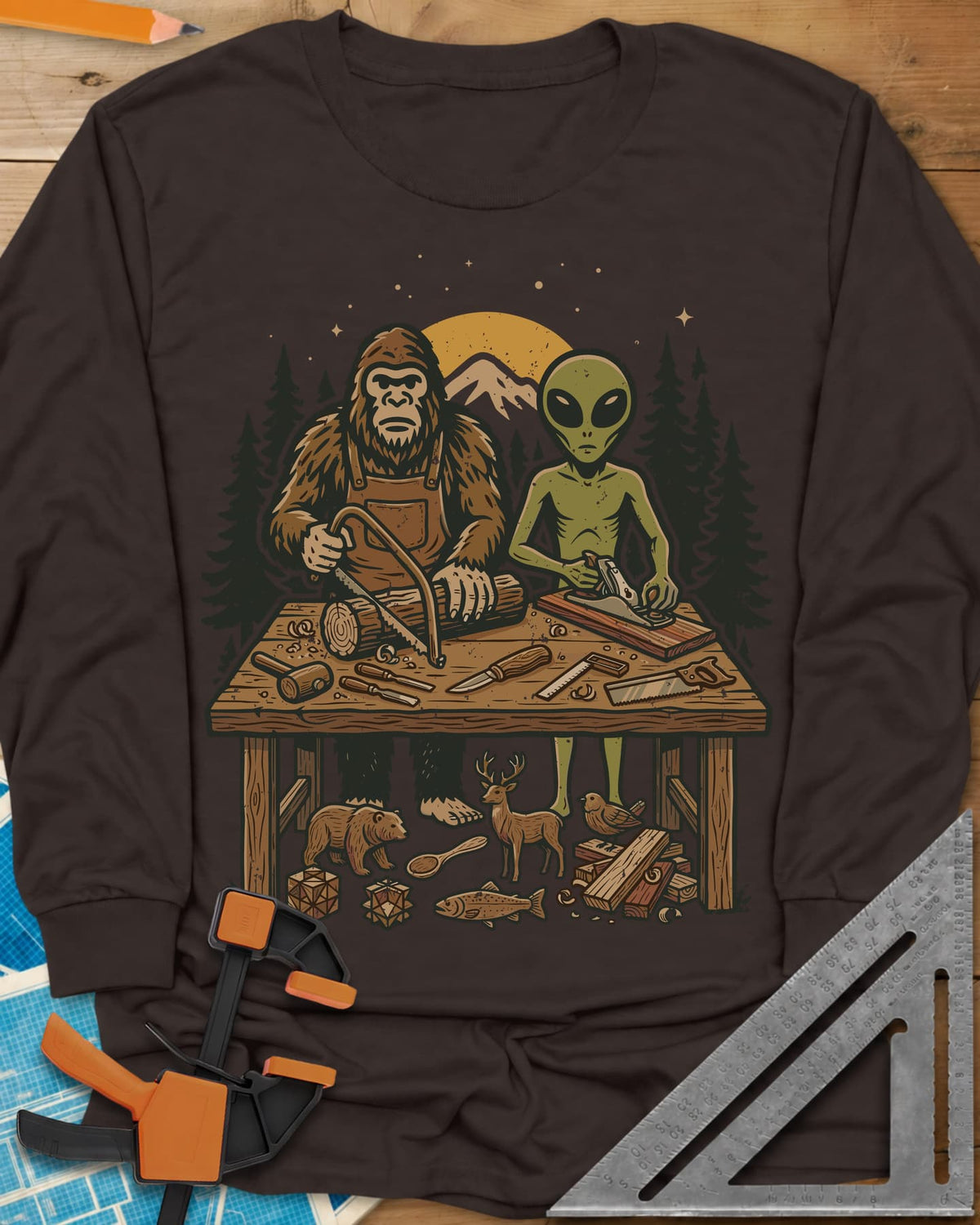Bigfoot And Alien Woodshop long sleeve shirt in Dark Chocolate, Bigfoot sawing a log and an alien planing a board at one