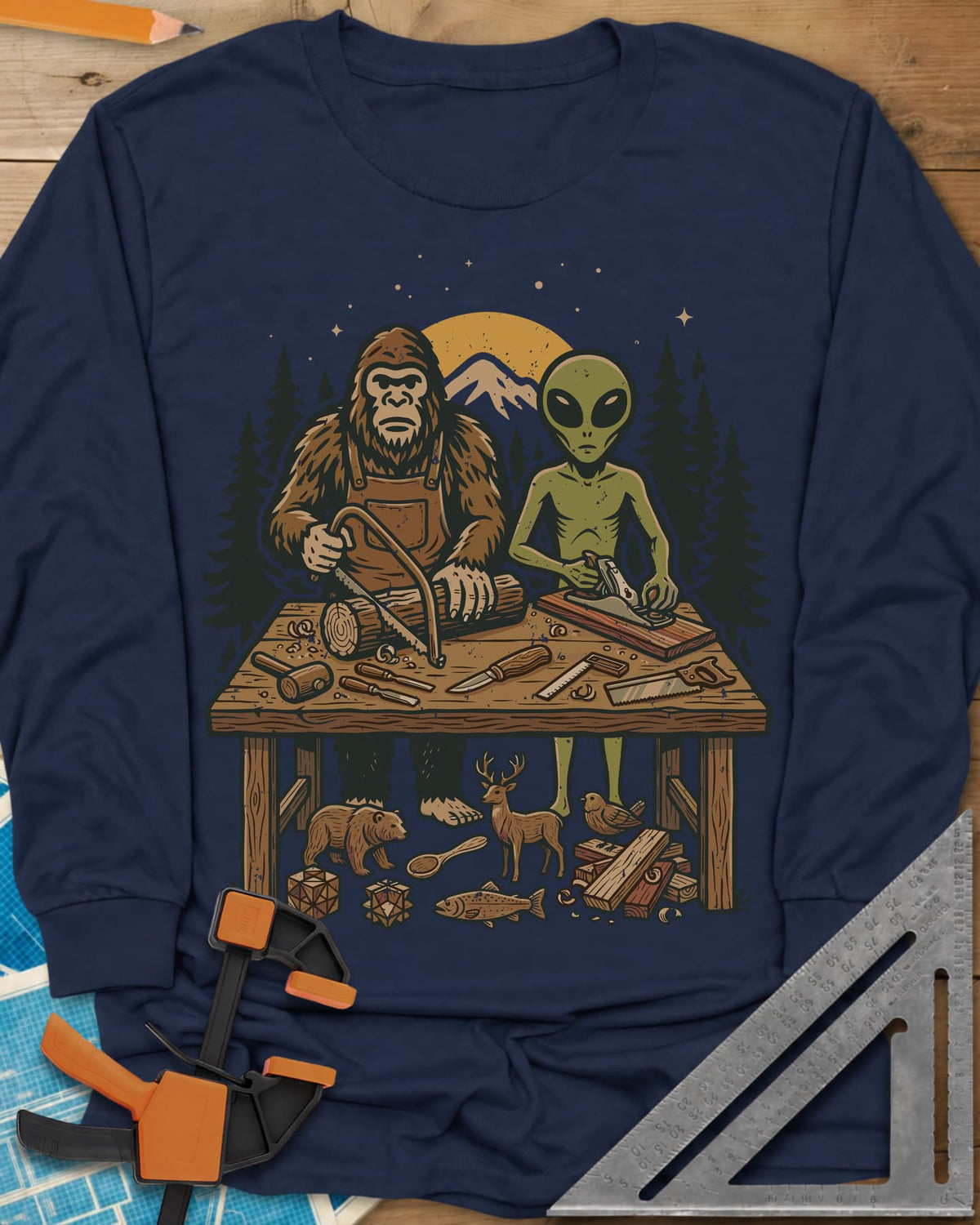 Bigfoot And Alien Woodshop long sleeve shirt in Navy, Bigfoot sawing a log and an alien planing a board at one bench