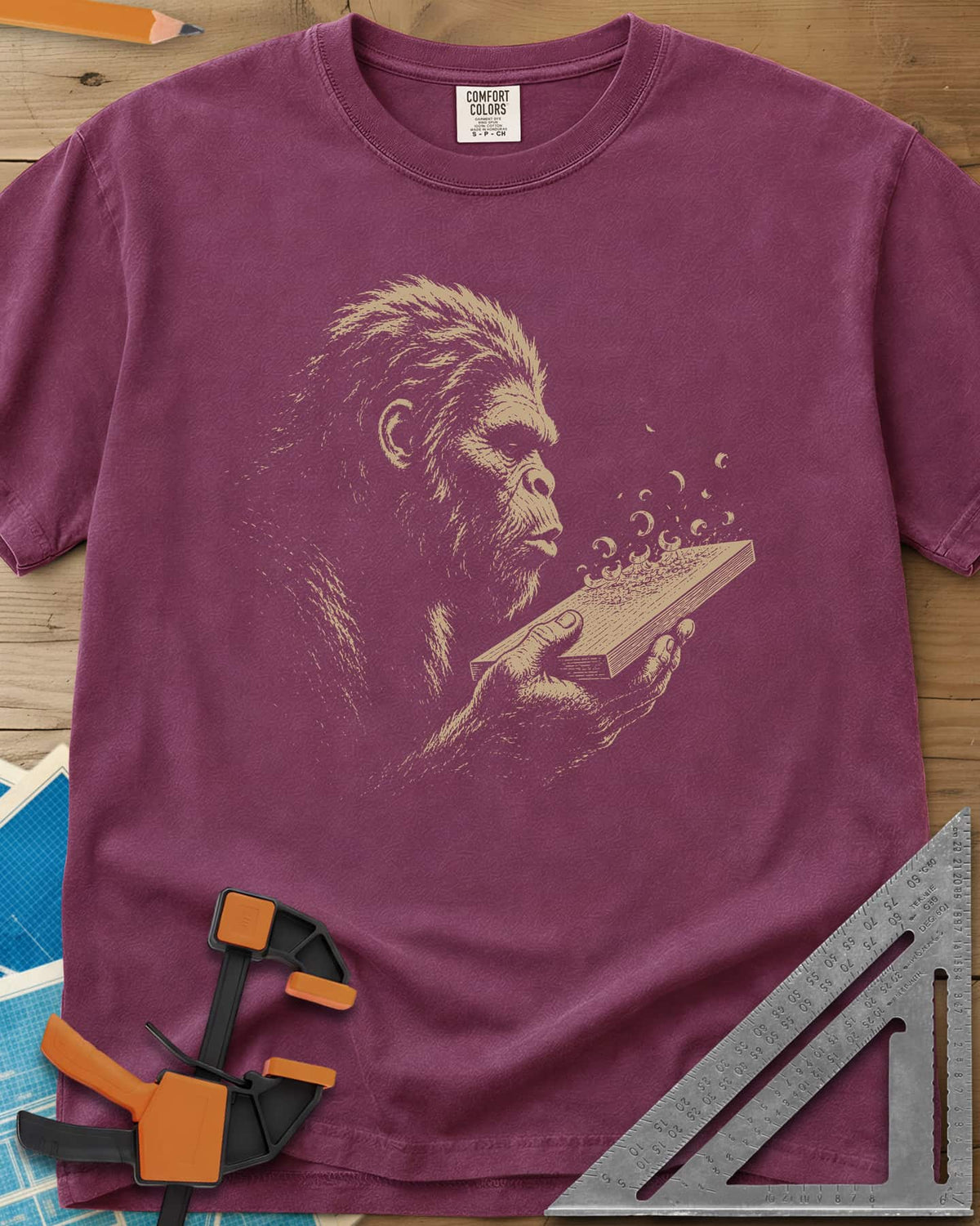 Bigfoot Blowing Sawdust heavyweight tee in Berry, Bigfoot in fine line work blowing sawdust curls off a board