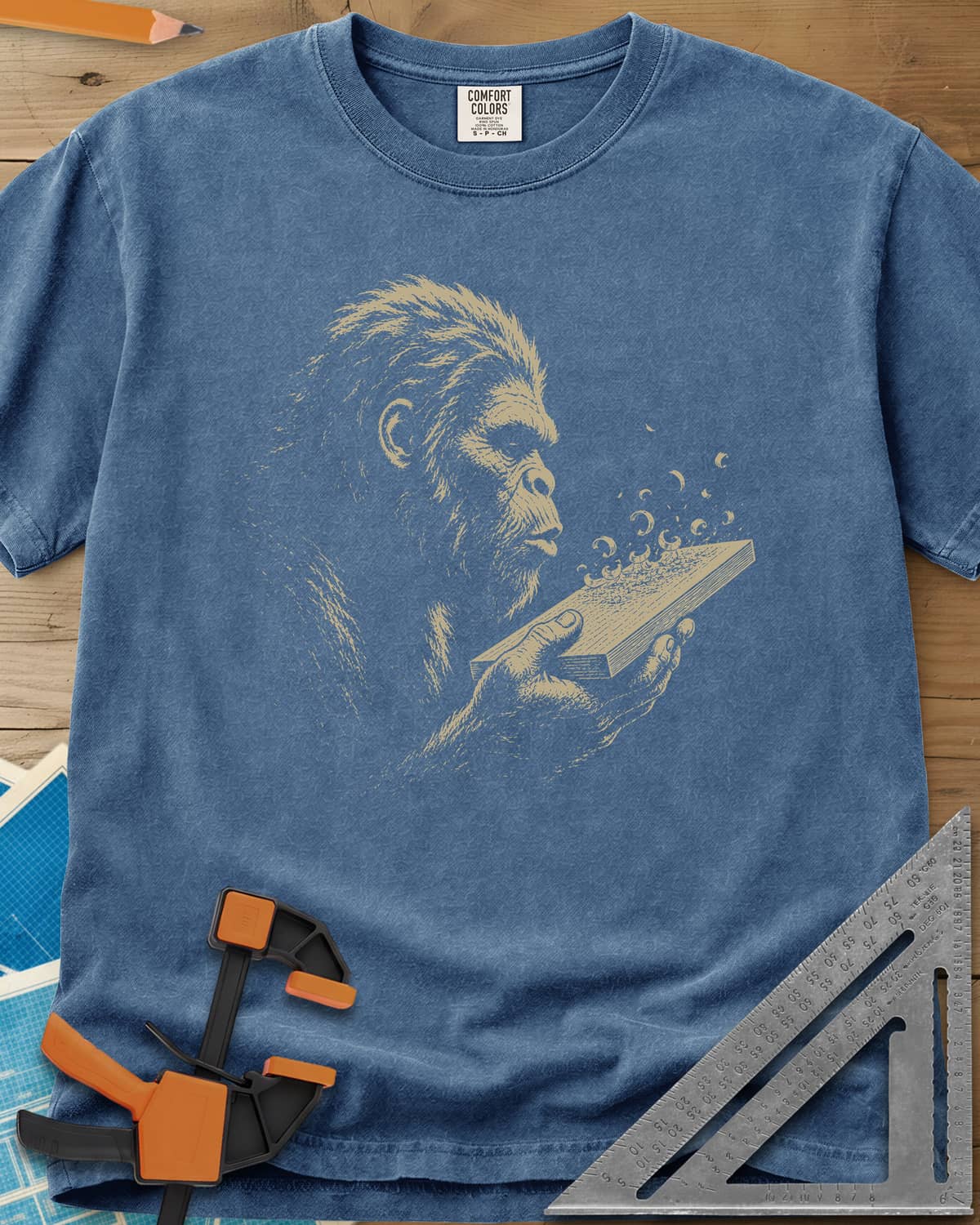 Bigfoot Blowing Sawdust heavyweight tee in Blue Jean, Bigfoot in fine line work blowing sawdust curls off a board