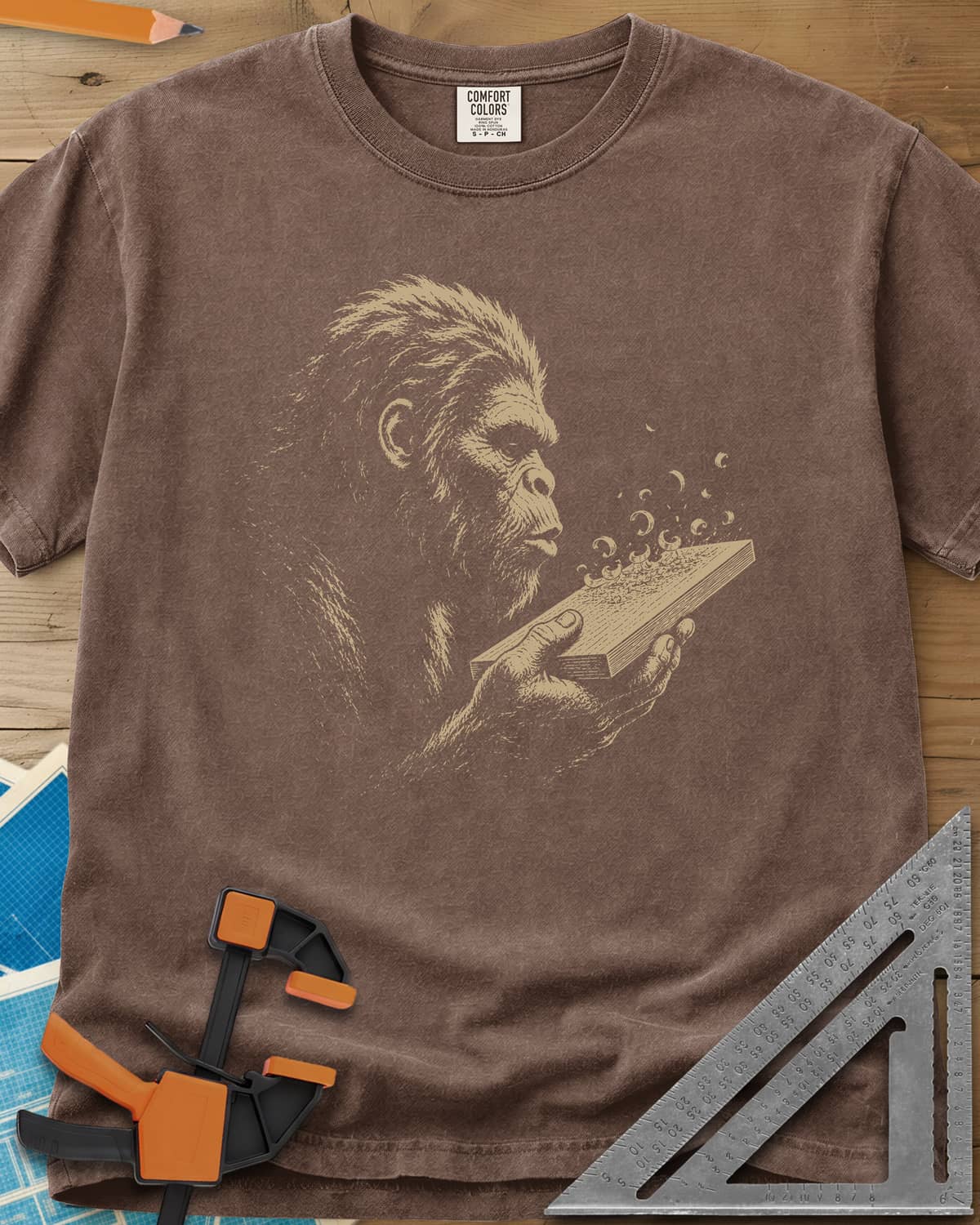 Bigfoot Blowing Sawdust heavyweight tee in Espresso, Bigfoot in fine line work blowing sawdust curls off a board