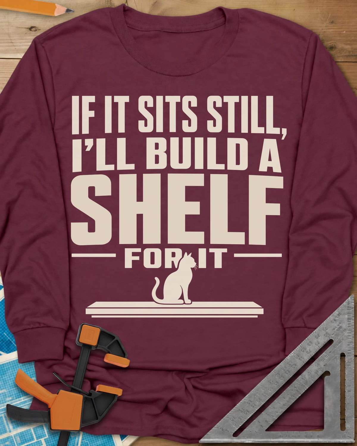 Build A Shelf long sleeve shirt in Maroon, a cat sitting on a plain shelf board under the words