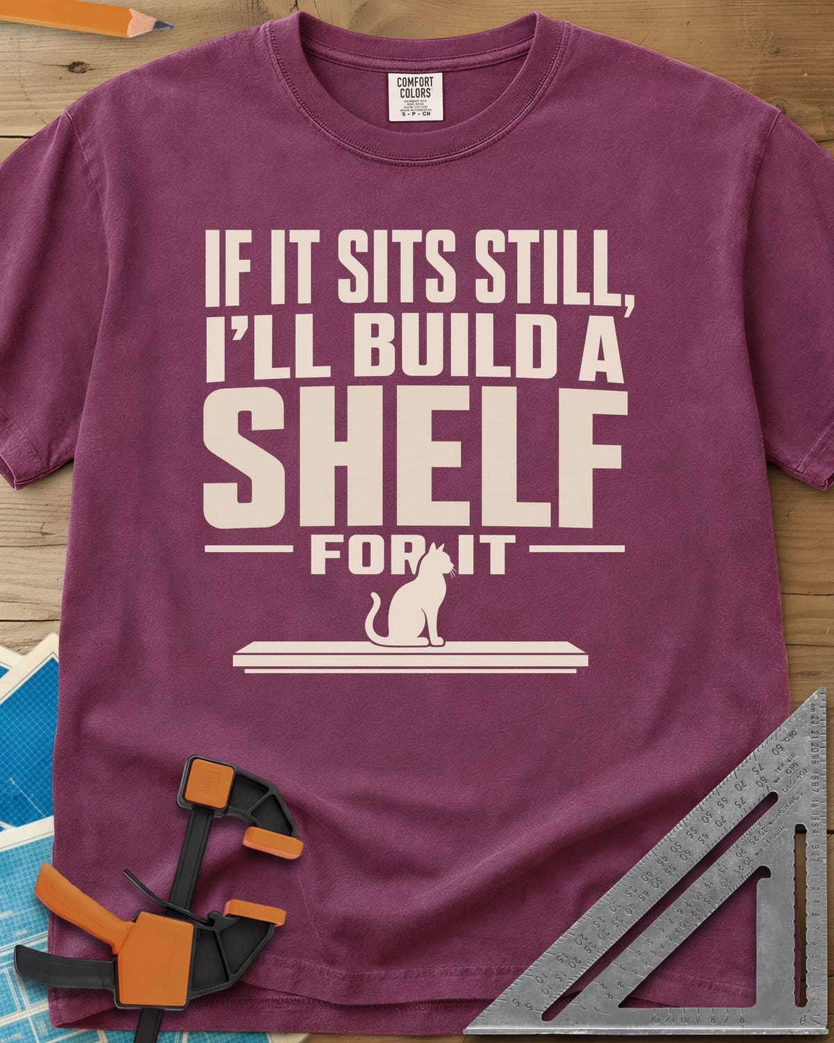 Build A Shelf heavyweight tee in Berry, a cat sitting on a plain shelf board under the words