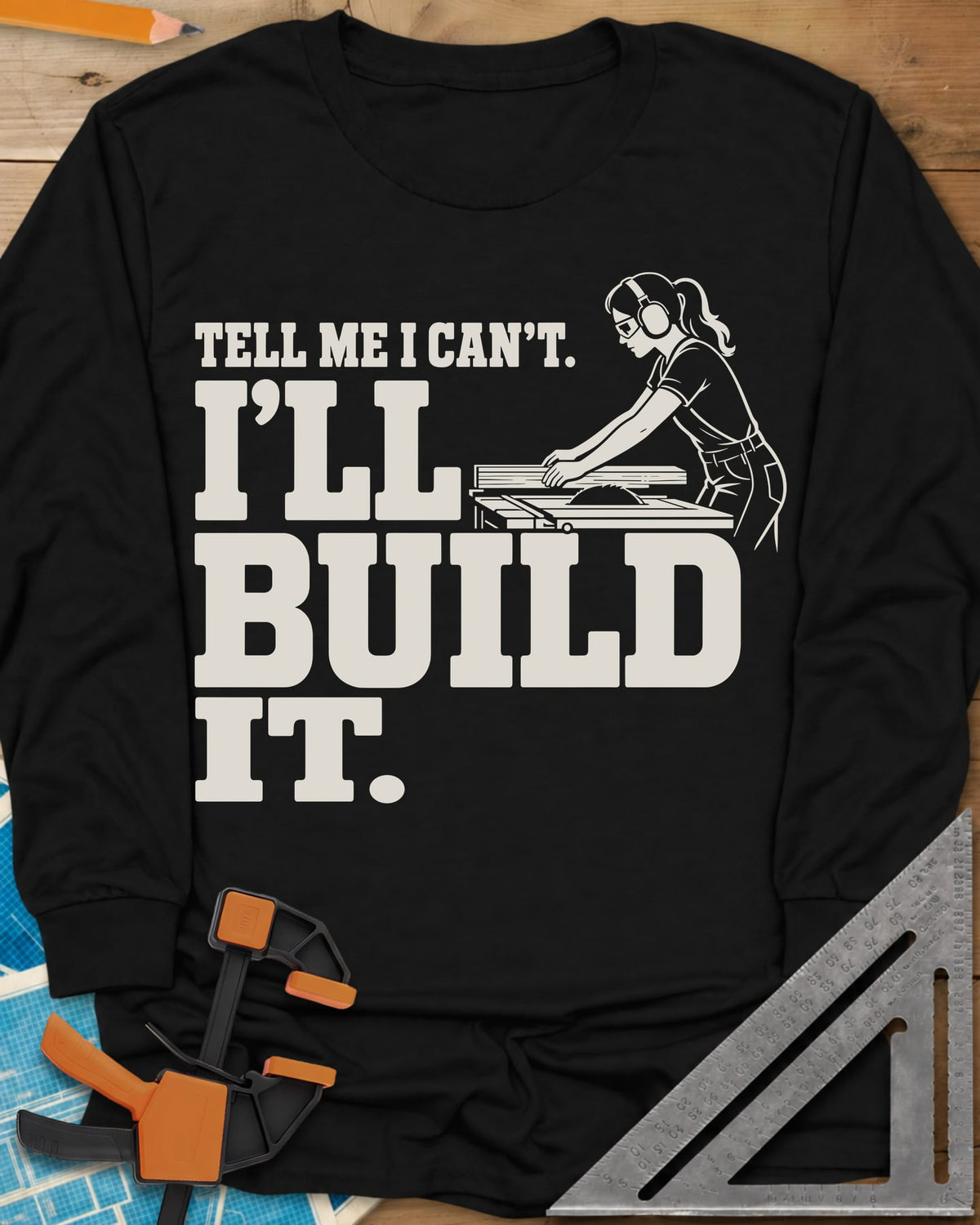 Build It long sleeve shirt in Black, a woman in ear protection and safety glasses at a table saw