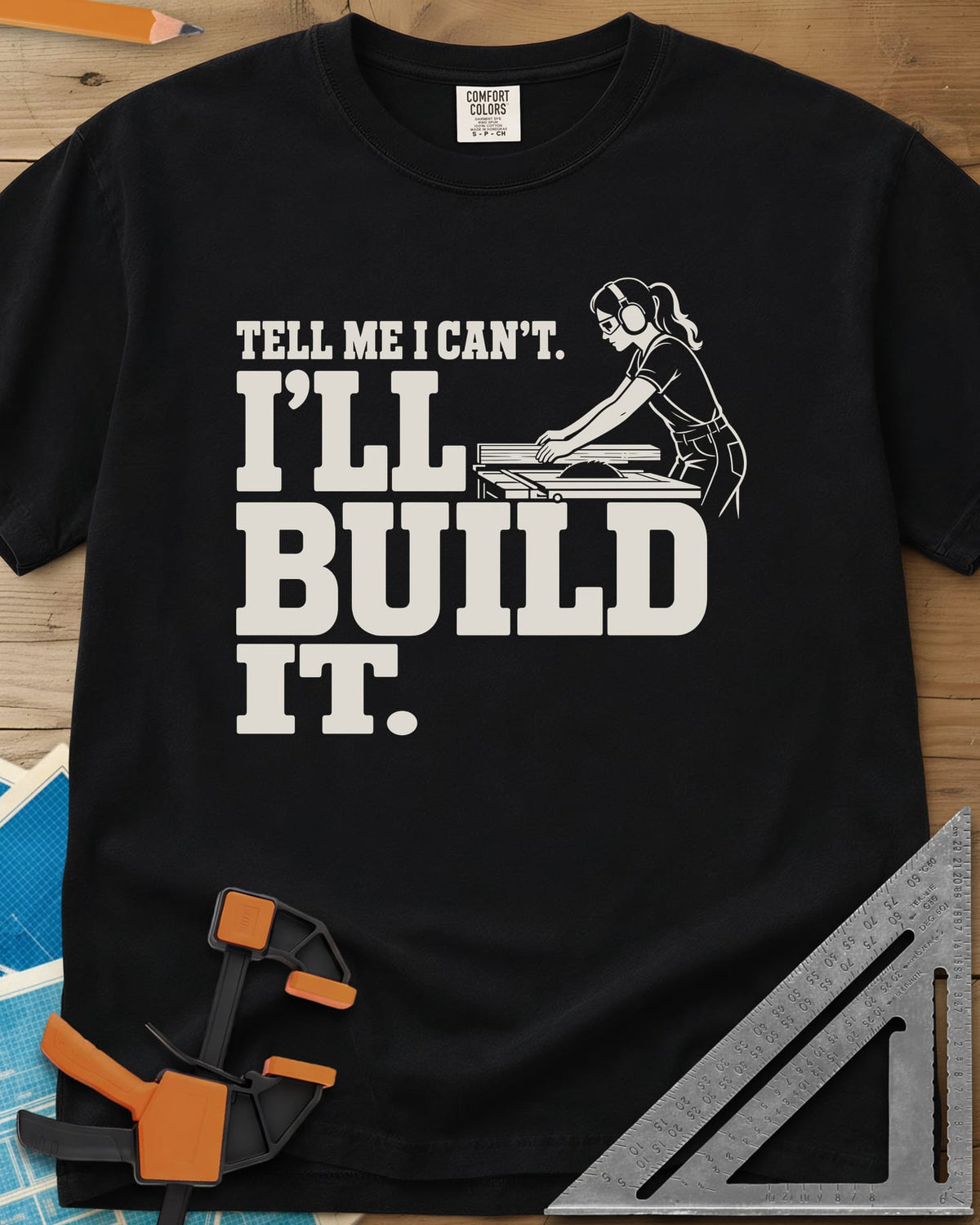 Build It heavyweight tee in Black, a woman in ear protection and safety glasses at a table saw