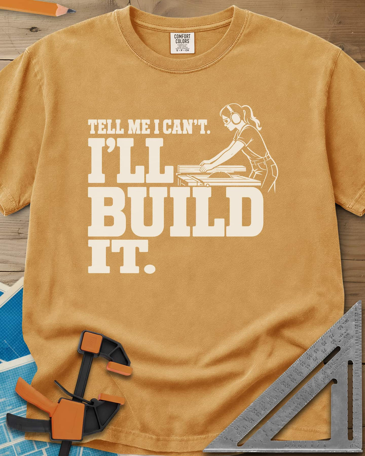 Build It heavyweight tee in Mustard, a woman in ear protection and safety glasses at a table saw