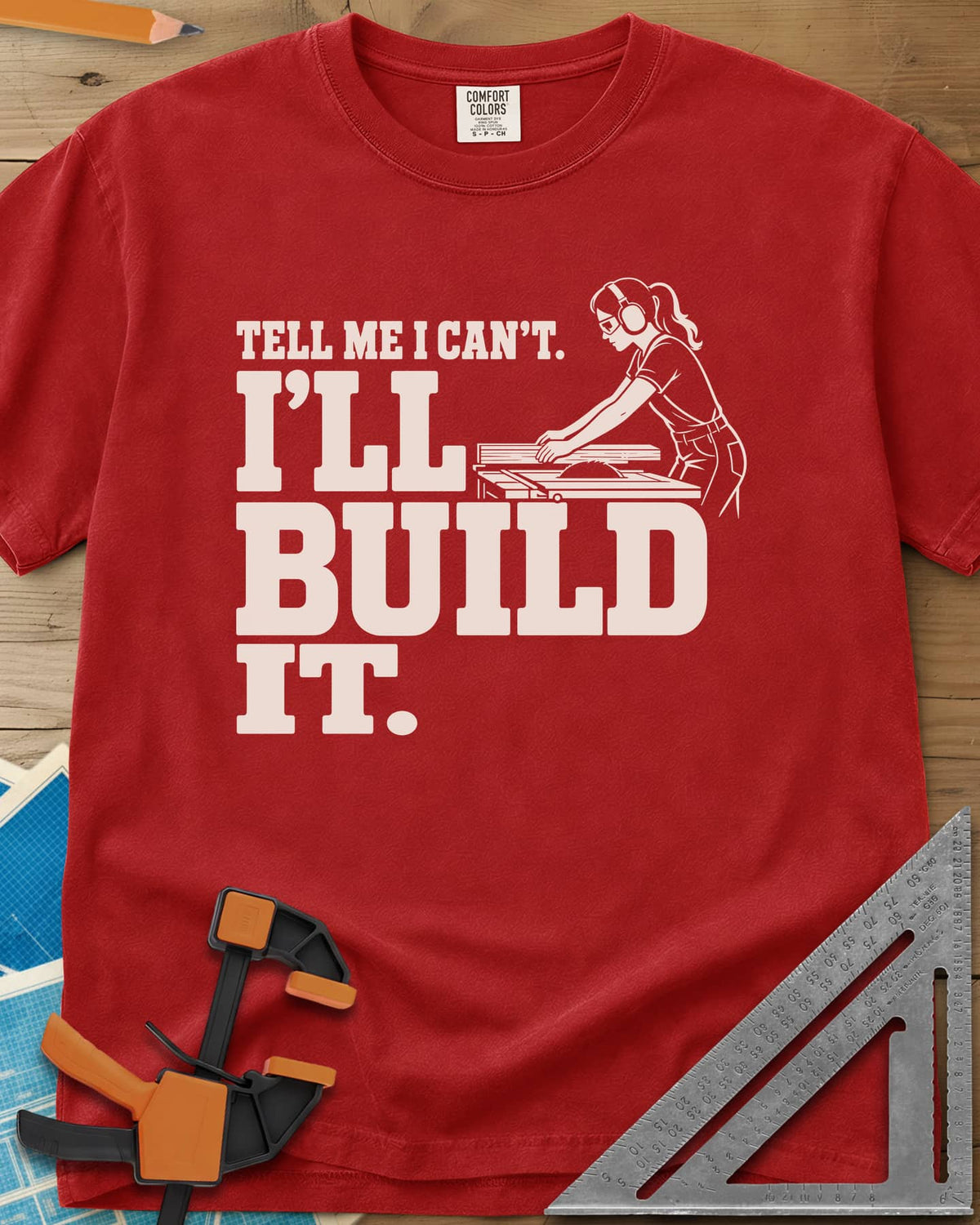 Build It heavyweight tee in Red, a woman in ear protection and safety glasses at a table saw