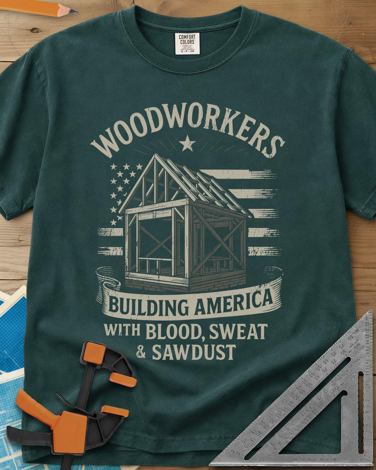 Building America heavyweight tee in Blue Spruce, a timber frame in front of a worn American flag