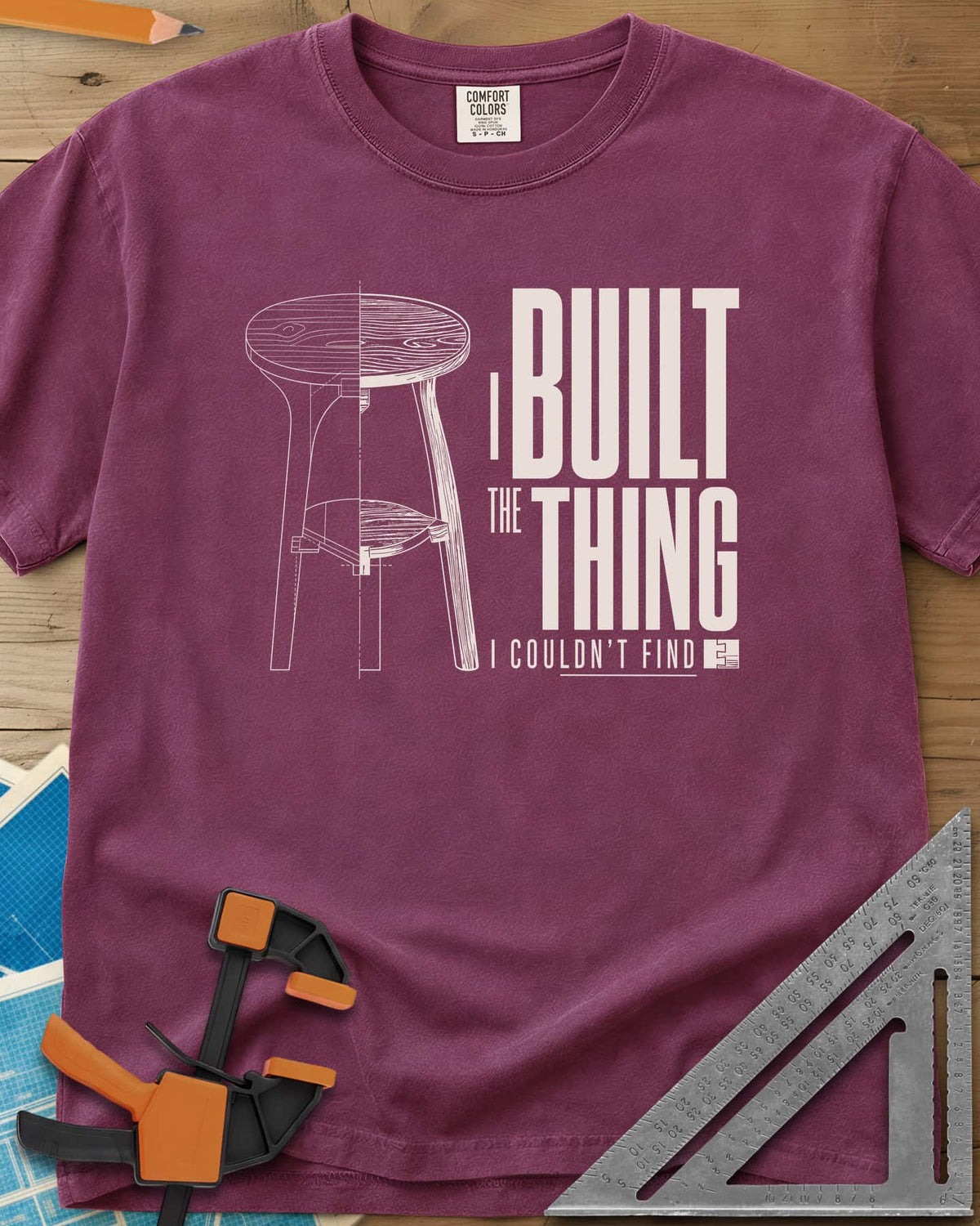 Built The Thing heavyweight tee in Berry, a three-legged stool drawn half blueprint, half wood grain