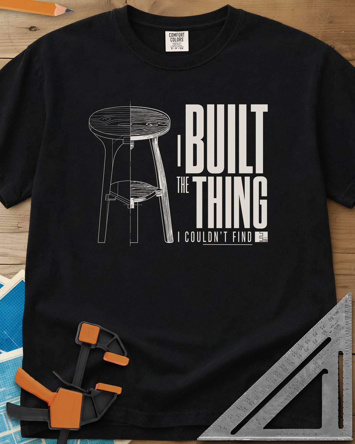 Built The Thing heavyweight tee in Black, a three-legged stool drawn half blueprint, half wood grain