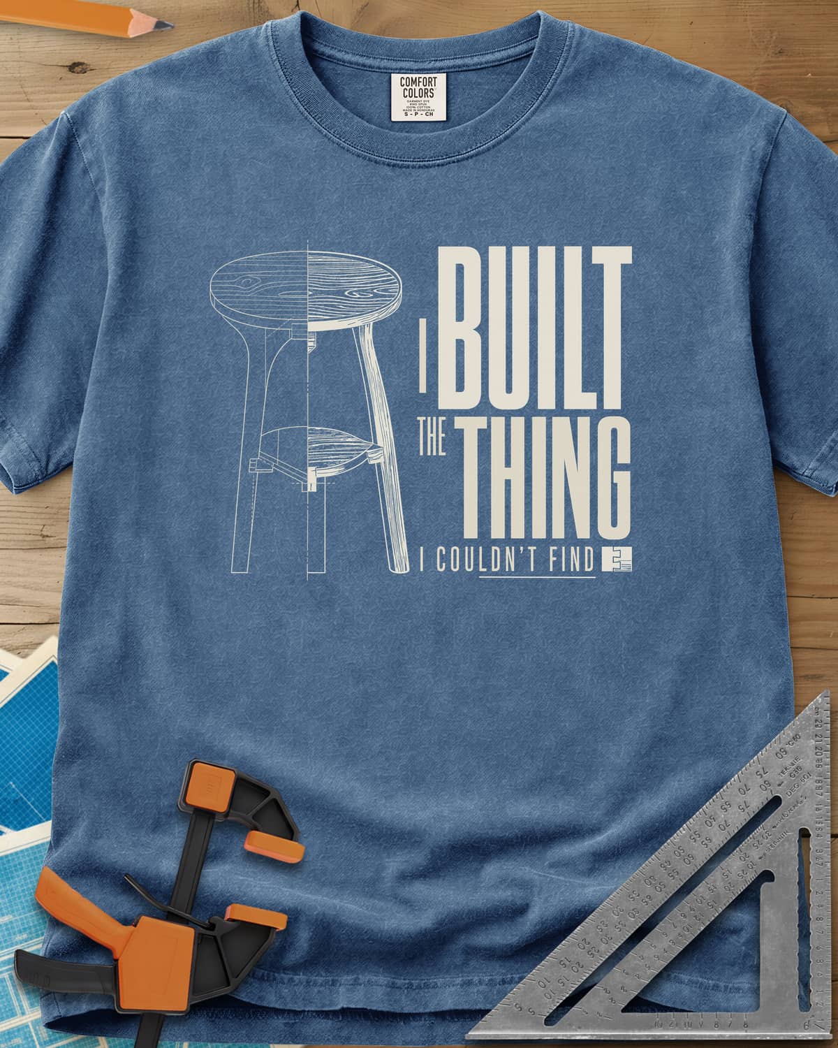 Built The Thing heavyweight tee in Blue Jean, a three-legged stool drawn half blueprint, half wood grain