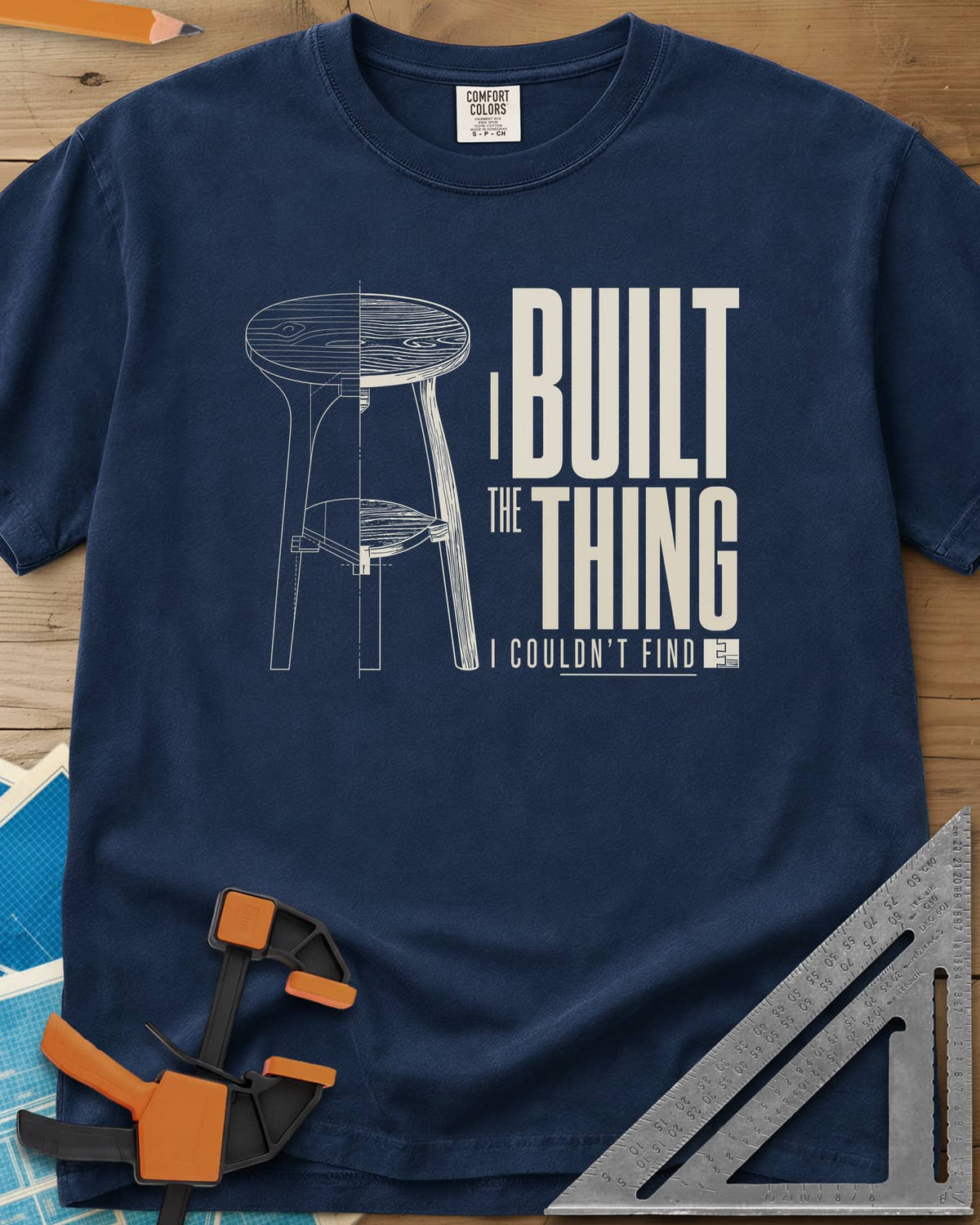 Built The Thing heavyweight tee in Navy, a three-legged stool drawn half blueprint, half wood grain
