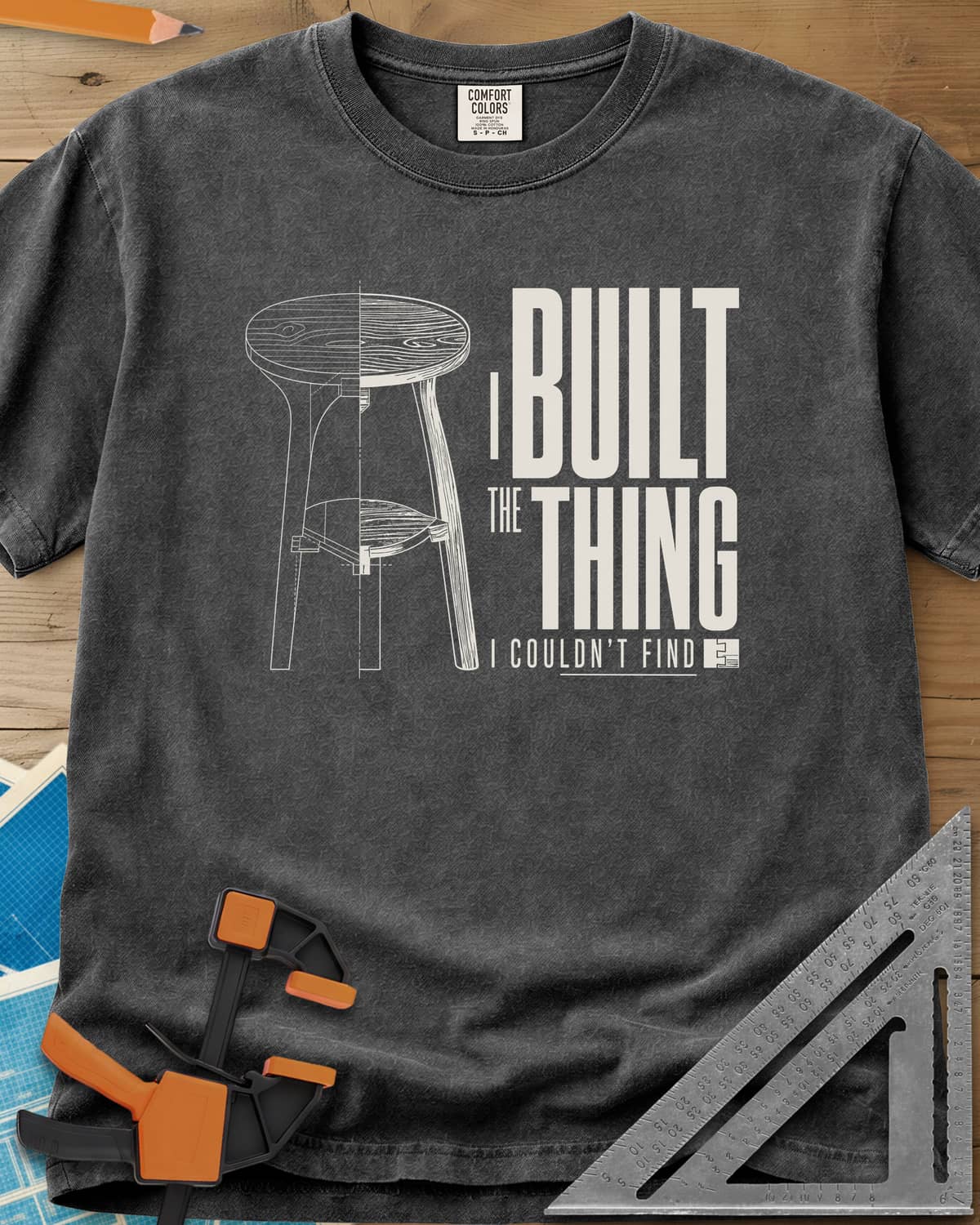 Built The Thing heavyweight tee in Pepper, a three-legged stool drawn half blueprint, half wood grain