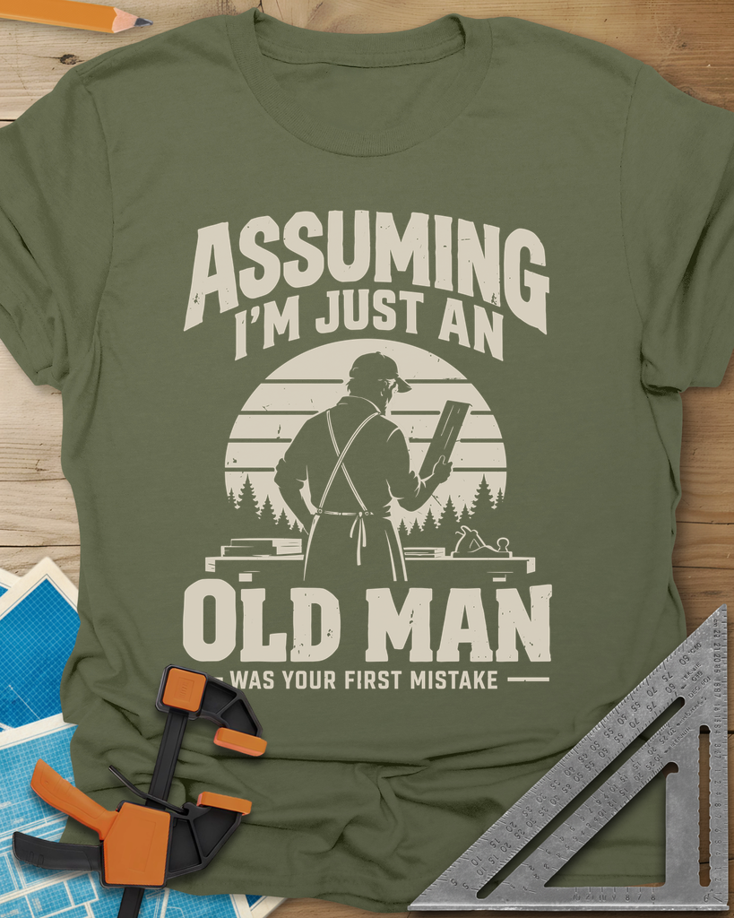 Old Man Mistake t-shirt in Military Green, a woodworker in an apron holding a board before a striped sunset