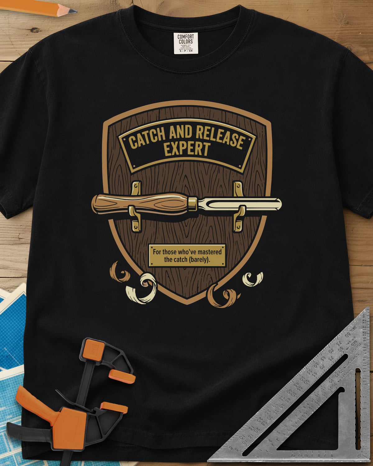 Catch and Release heavyweight tee in Black, a wooden shield plaque with a turning gouge and brass nameplate