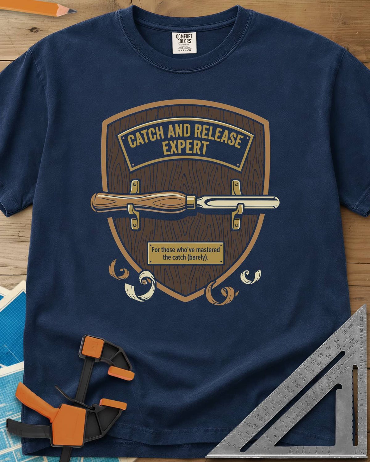 Catch and Release heavyweight tee in Navy, a wooden shield plaque with a turning gouge and brass nameplate