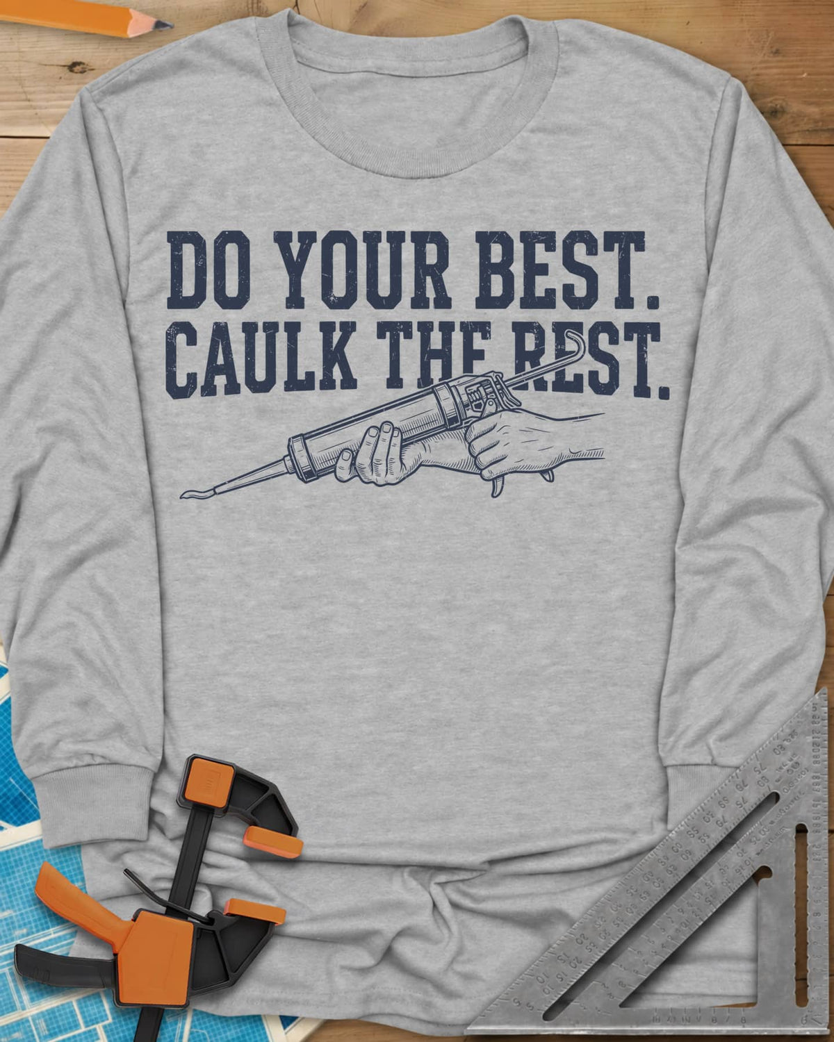 Caulk The Rest long sleeve shirt in Sport Grey, hands working a caulk gun under two lines of block lettering