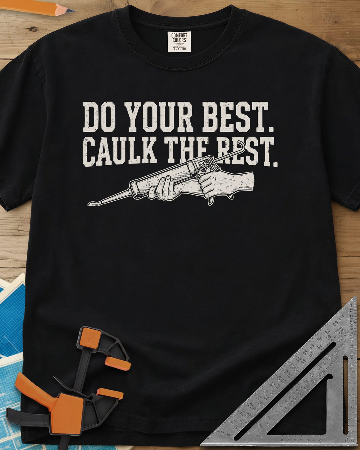 Caulk The Rest heavyweight tee in Black, hands working a caulk gun under two lines of block lettering
