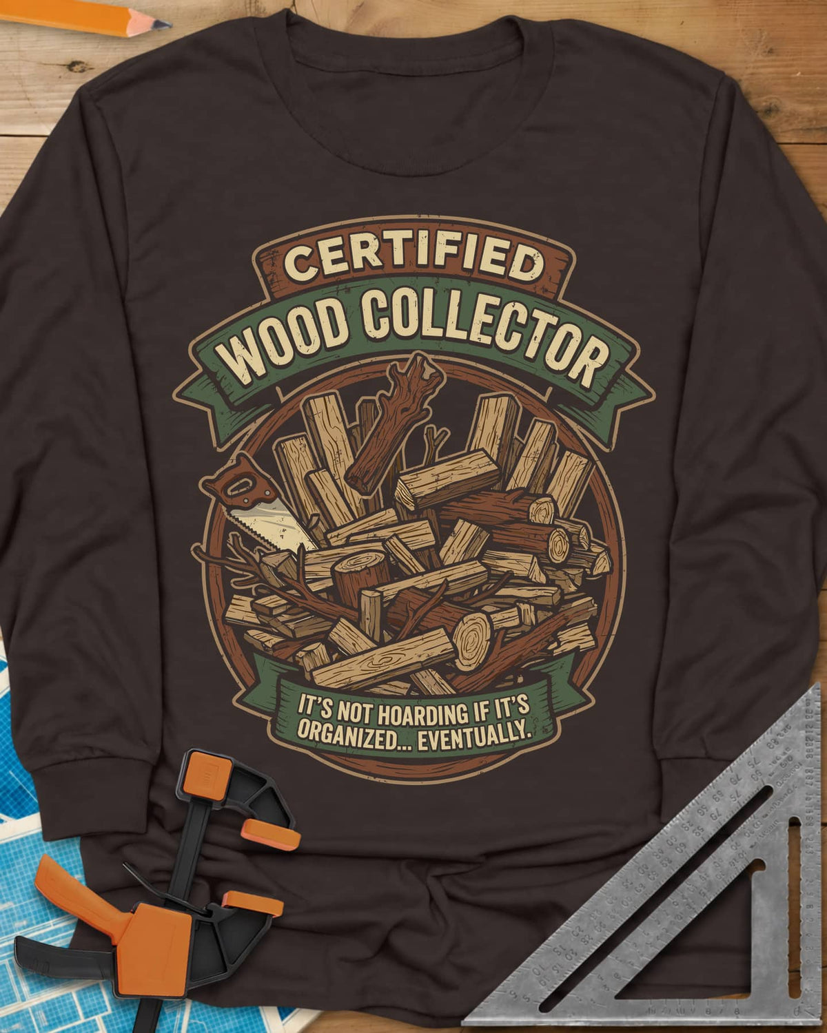 Certified Wood Collector long sleeve shirt in Dark Chocolate, ribbon banners over a heap of logs, offcuts and a handsaw