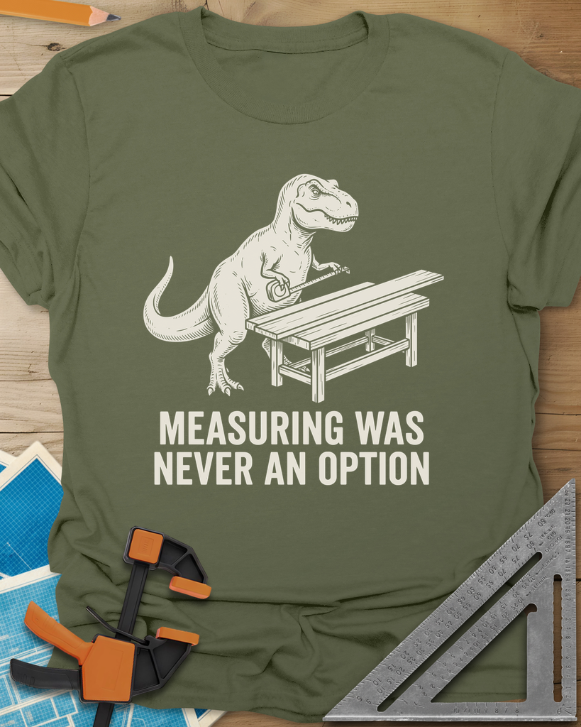 Dino Measuring t-shirt in Military Green, a T. rex with a tape measure beside a plank workbench
