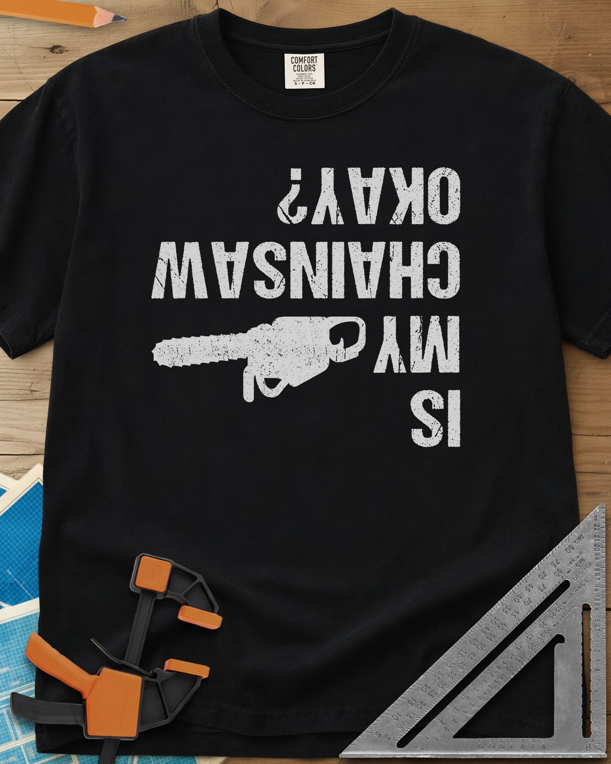 Chainsaw Okay? heavyweight tee in Black, upside-down distressed lettering beside a chainsaw on its side