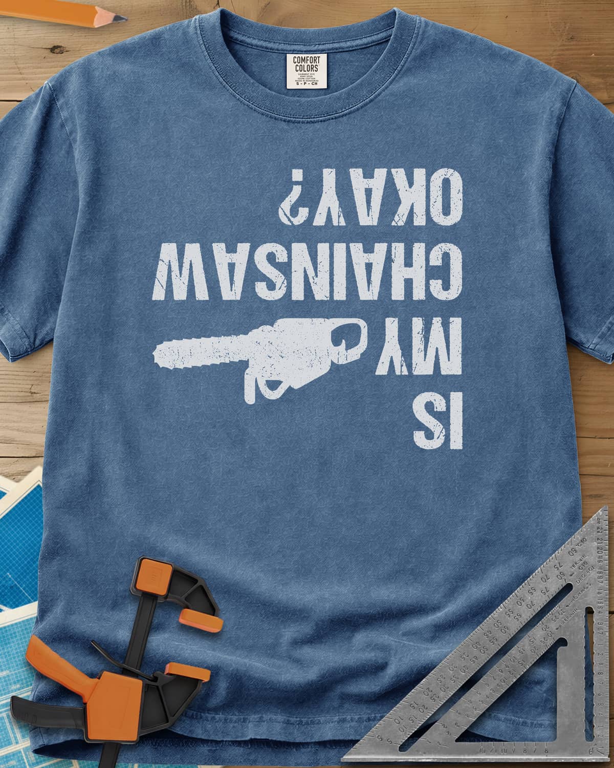 Chainsaw Okay? heavyweight tee in Blue Jean, upside-down distressed lettering beside a chainsaw on its side